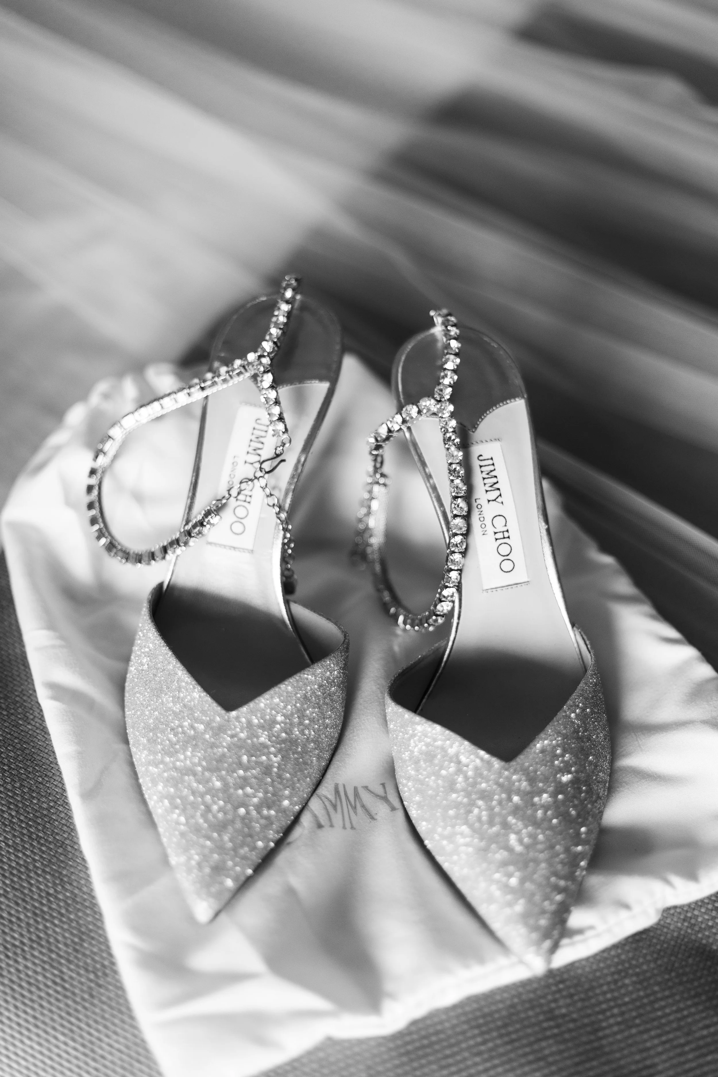Sparkly Jimmy Choo high-heeled shoes with rhinestone ankle straps on a satin pouch.