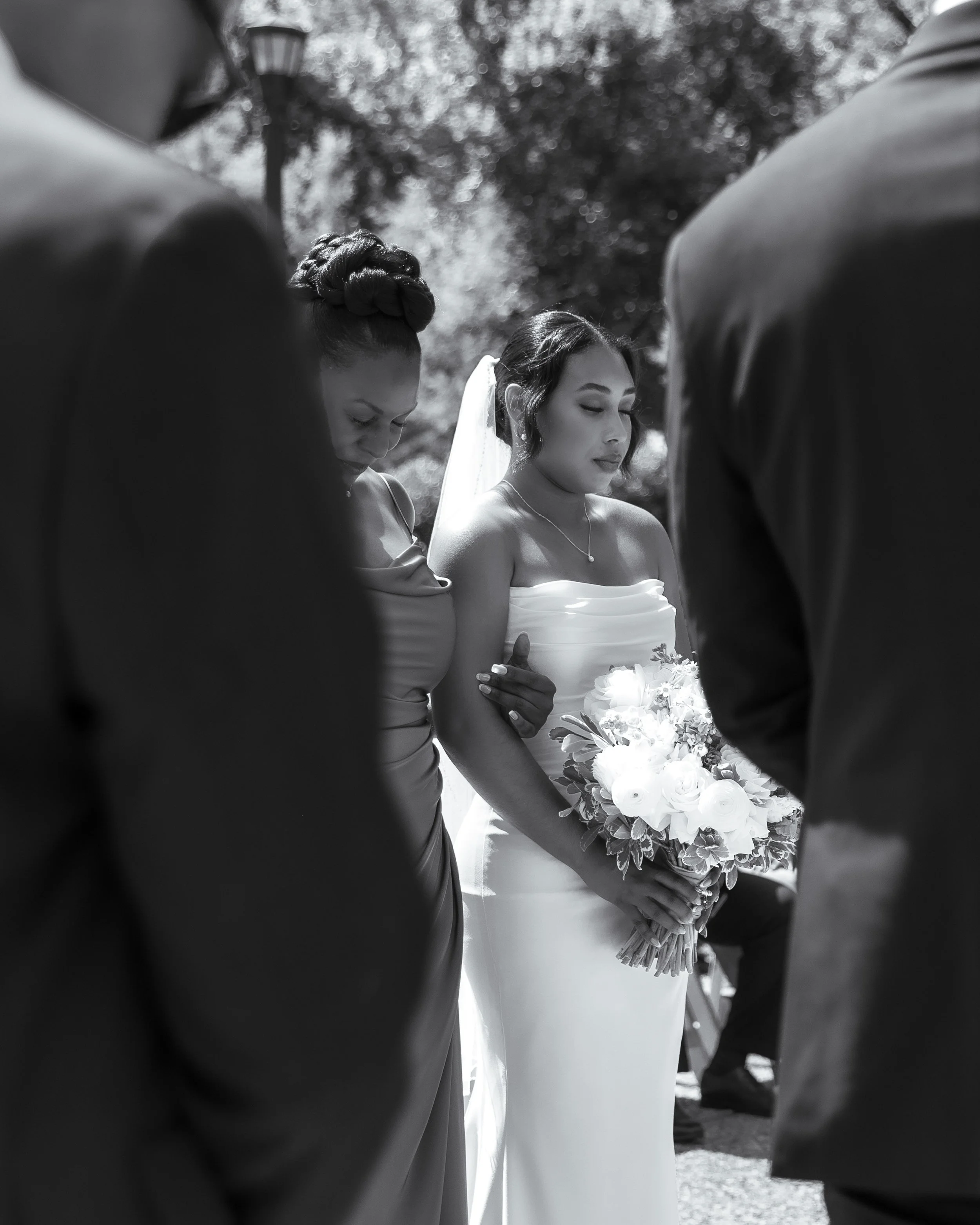 A bride holding a bouquet, surrounded by people at a wedding ceremony.
