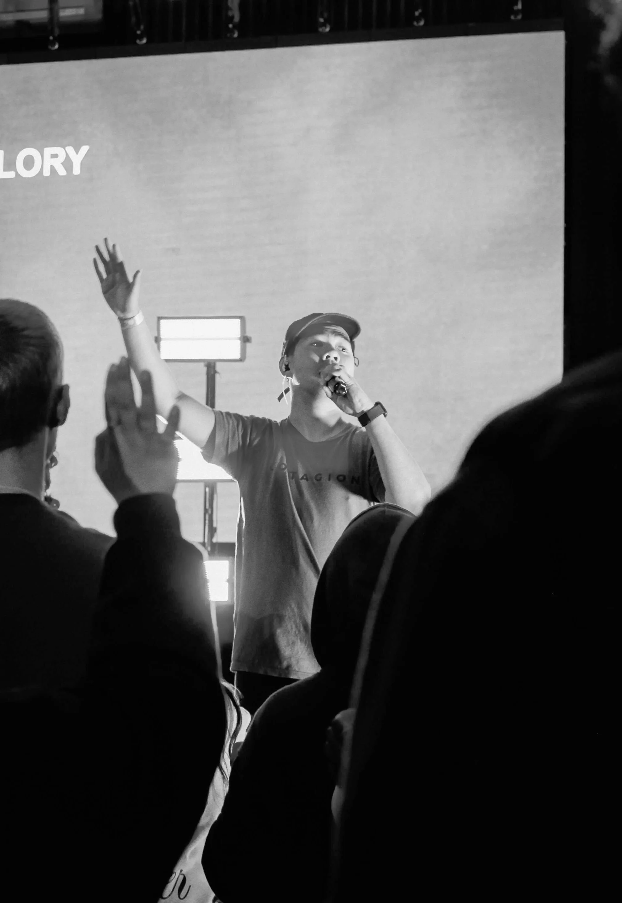 Joel, co-founder of vssls worship, leading worship with a microphone during a worship gathering where attendees worship with hands raised.