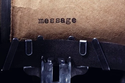 Close-up of a typewriter typing the word 'message' on a piece of paper.
