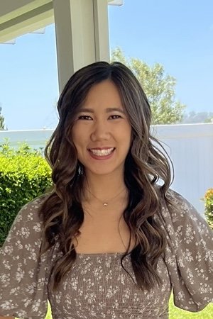 Young woman with long wavy hair smiling outdoors on a sunny day
