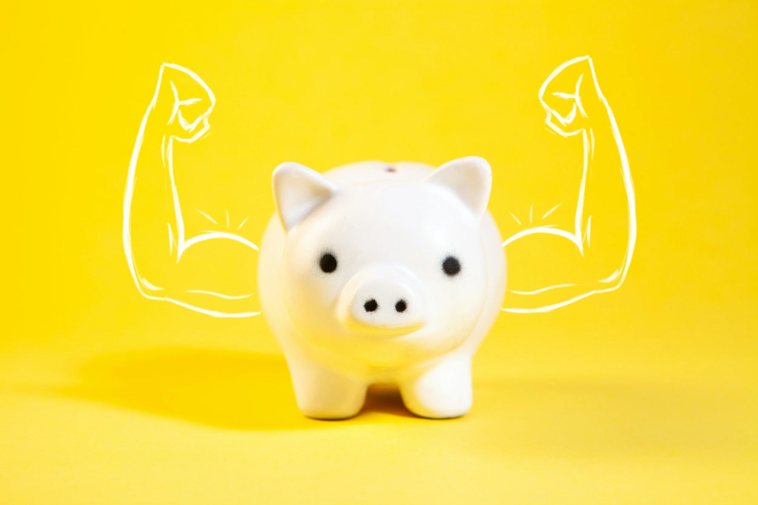 White piggy bank with drawn muscular arms flexing on a yellow background.