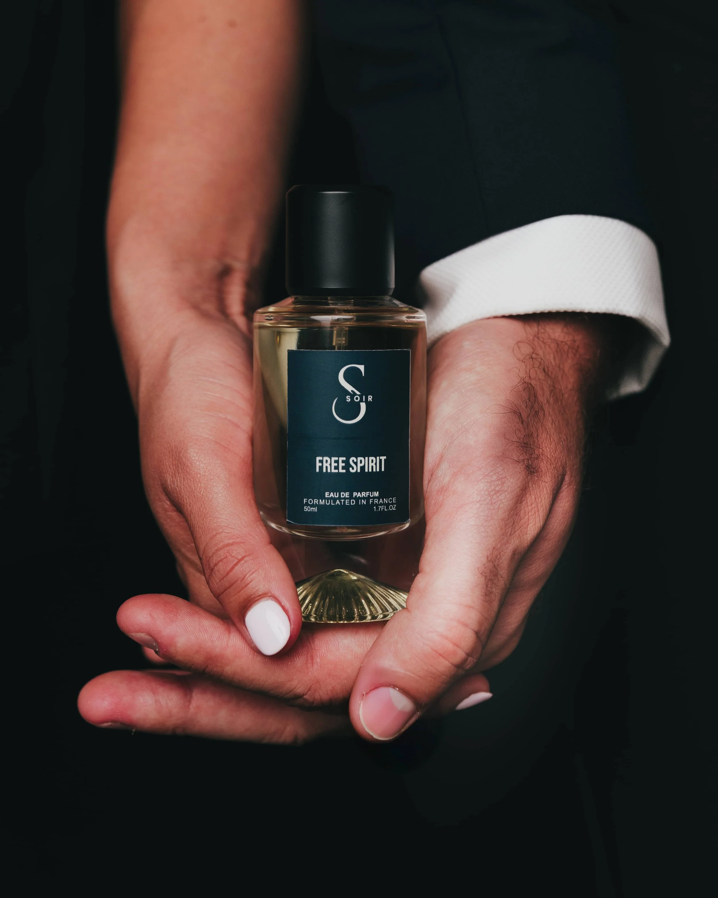 two hands, male and female holding a bottle of perfum