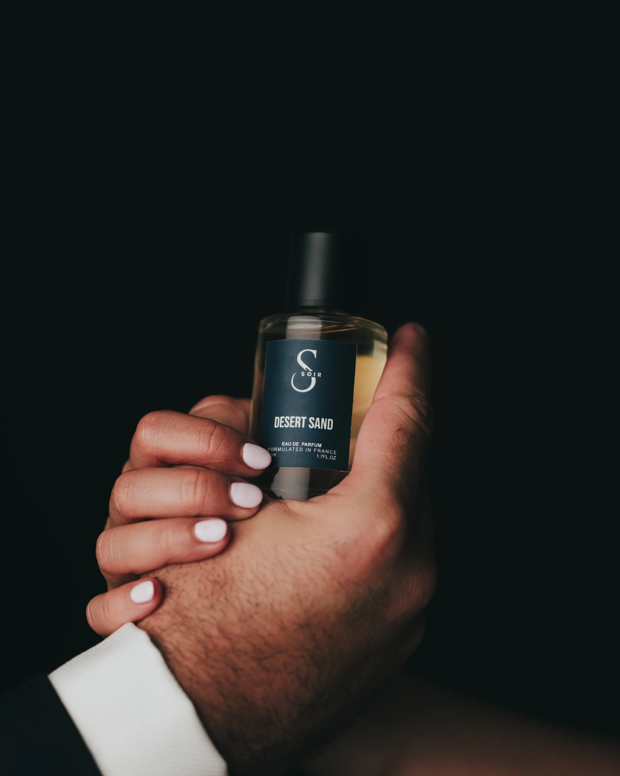 two hand, male and female holding a unisex bottle of perfum