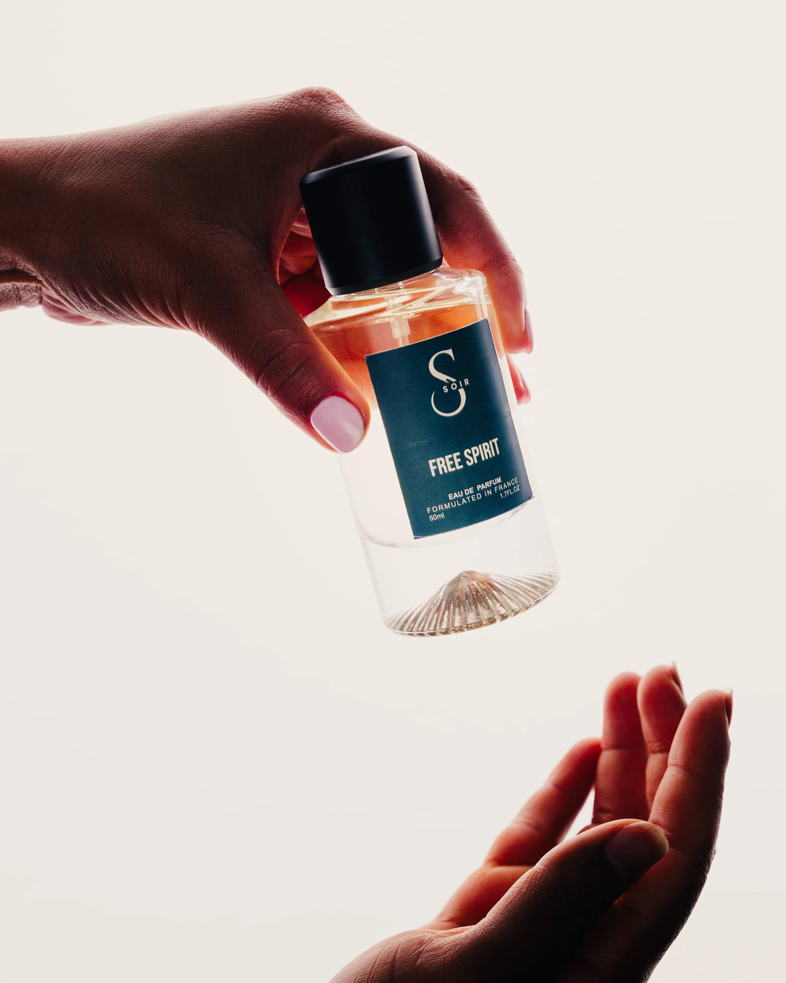 two women hand with a bottle of perfum 