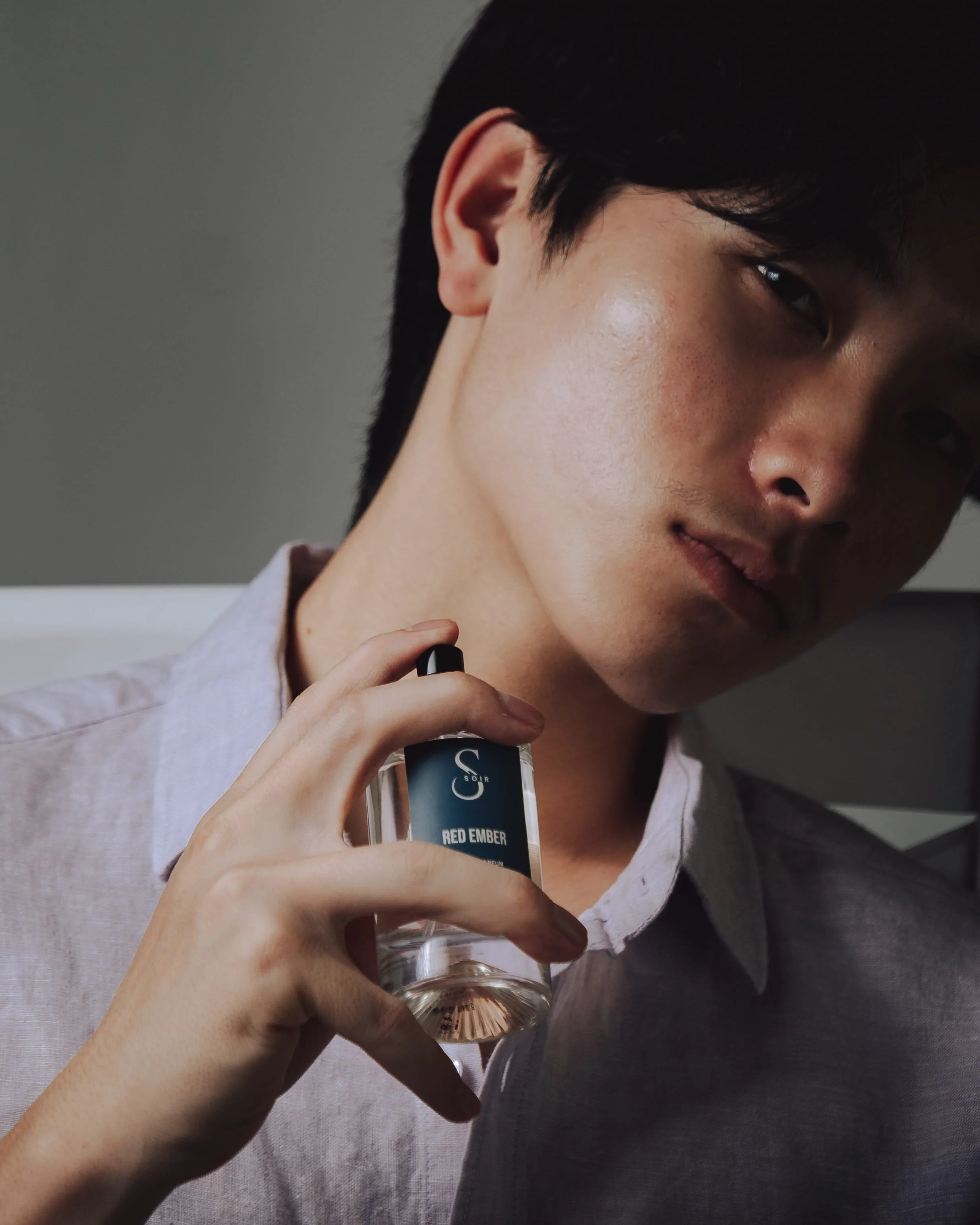 man holding bottle of perfum around his neck