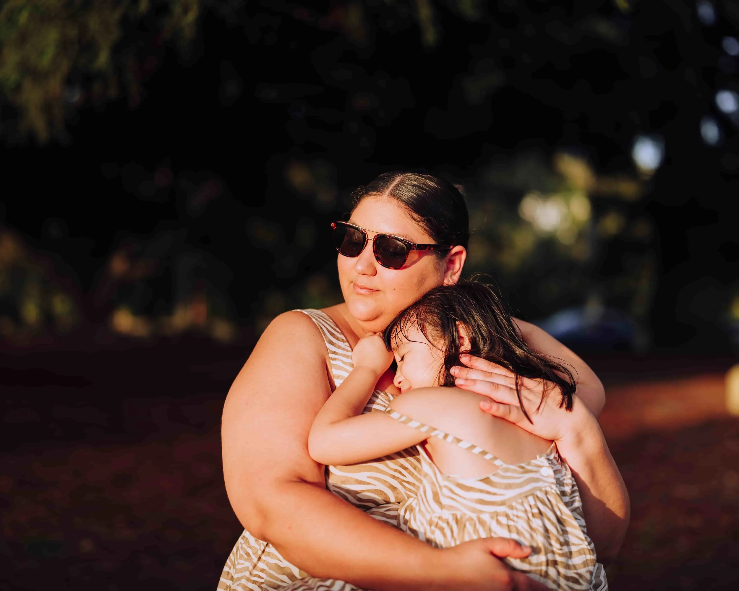 Mother hugging her daughter during sunset