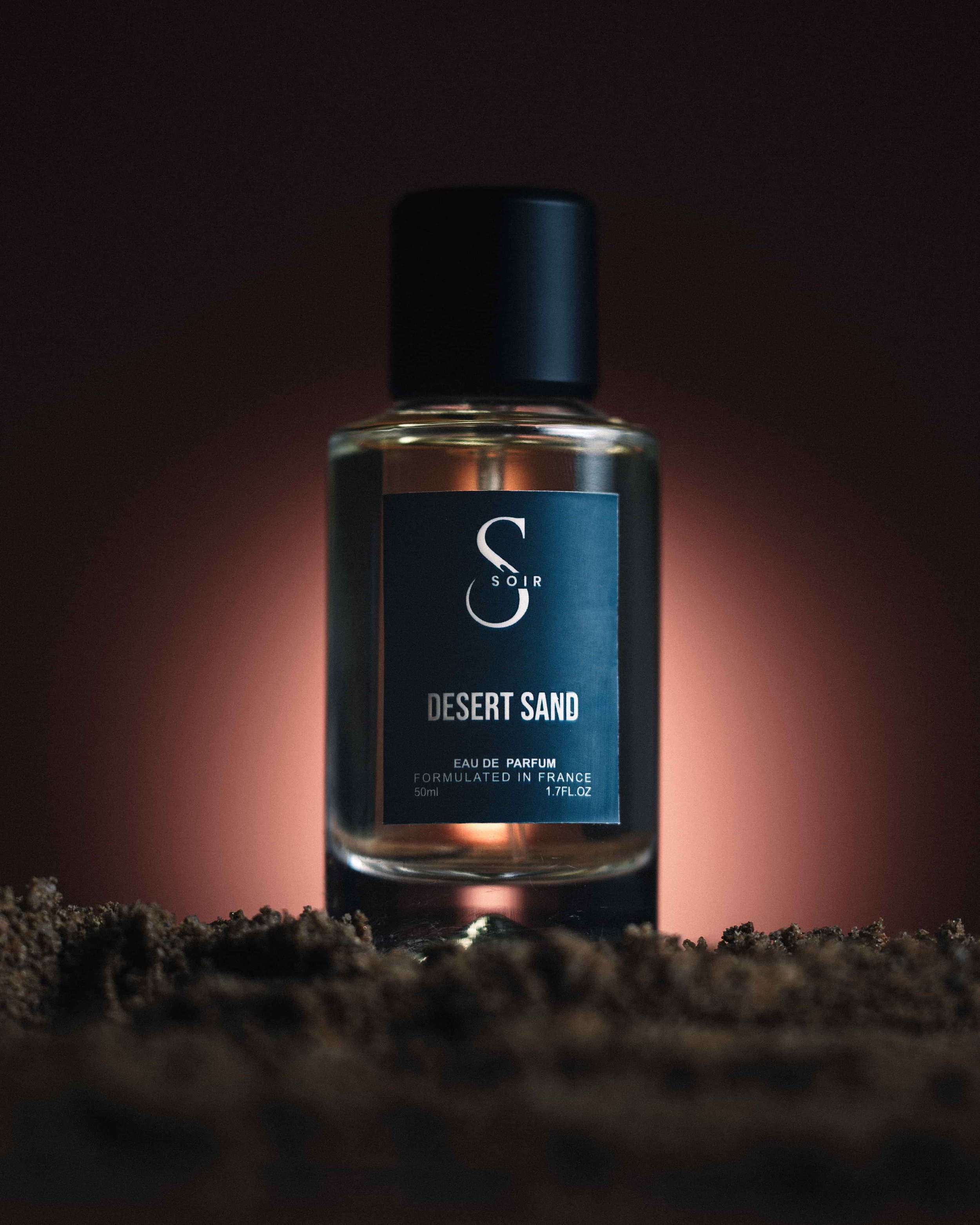 bottle of perfum on sand with illuminated backdrop