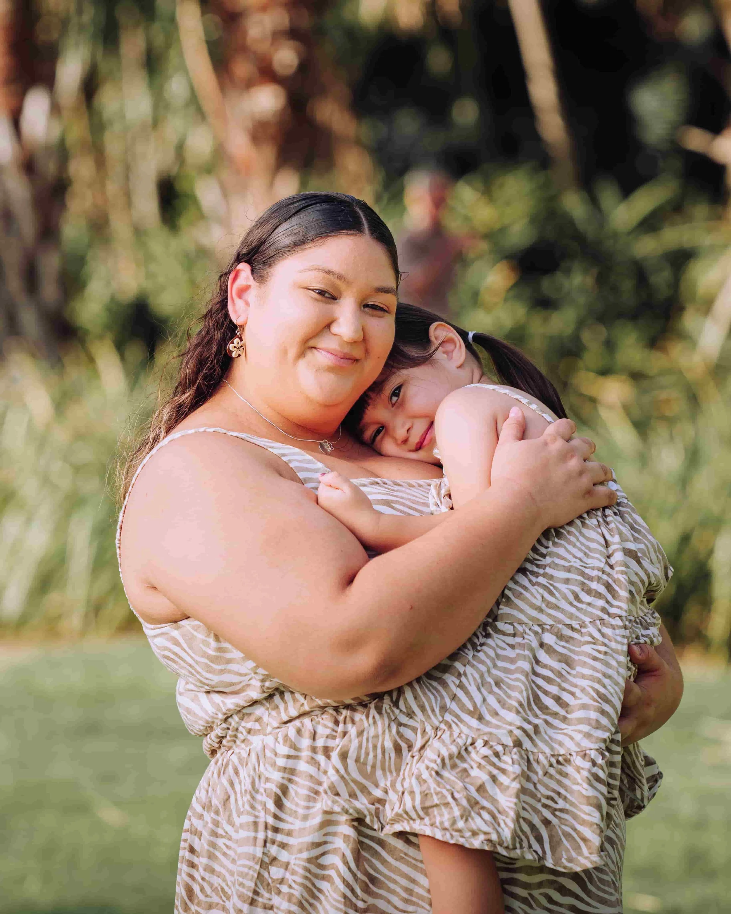 Mother hugging girl in park