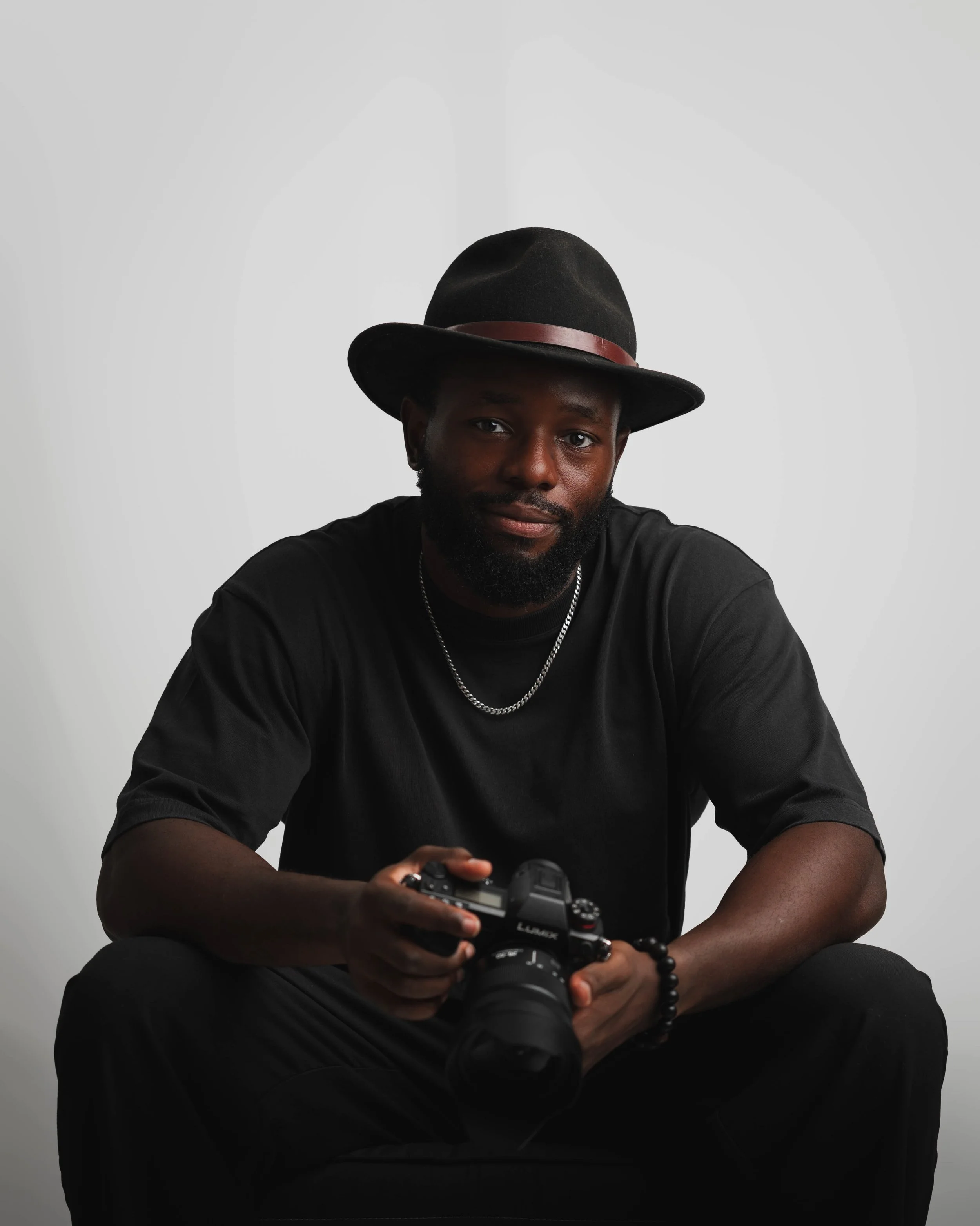 Man in black hat and shirt with camera on white background. Ideal for creative branding and headshots.