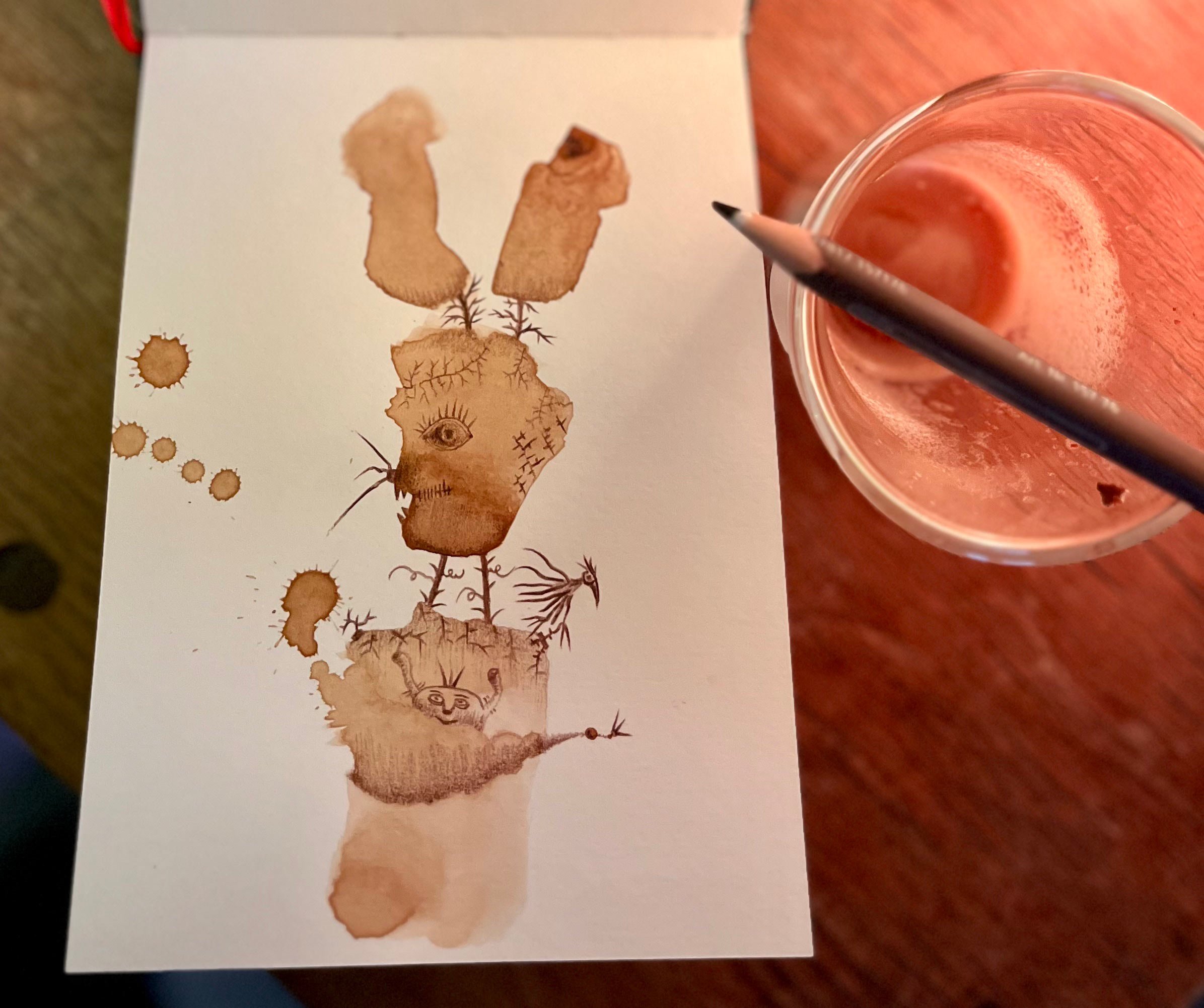 Une illustration faite avec du café, représentant un lapin avec un œil humain à la base, un visage de singe, et diverses racines et tiges qui ressemblent à une créature fantastique.