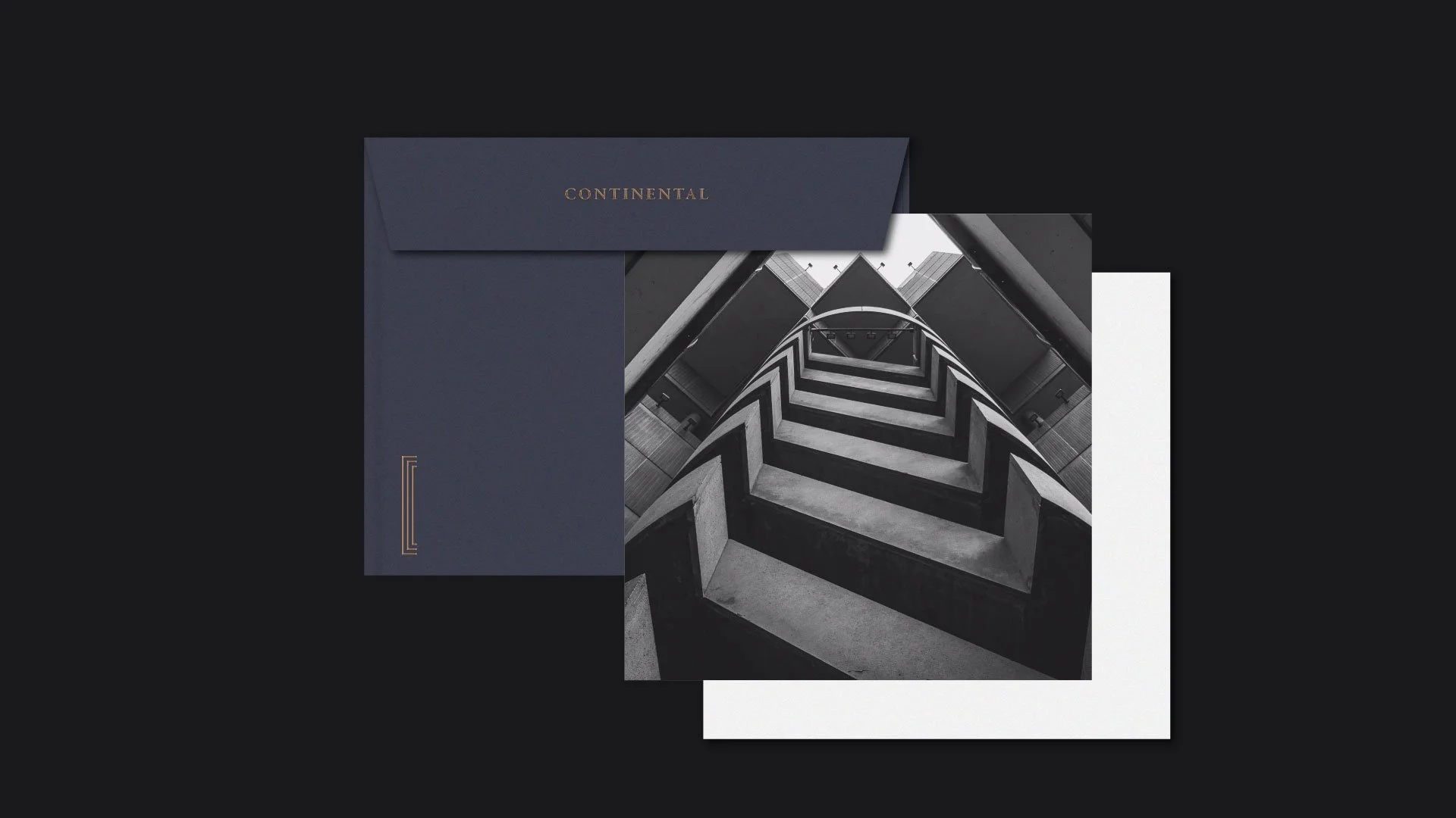 Black and white photograph of a modern building's stairwell looking up, with an angular geometric design.