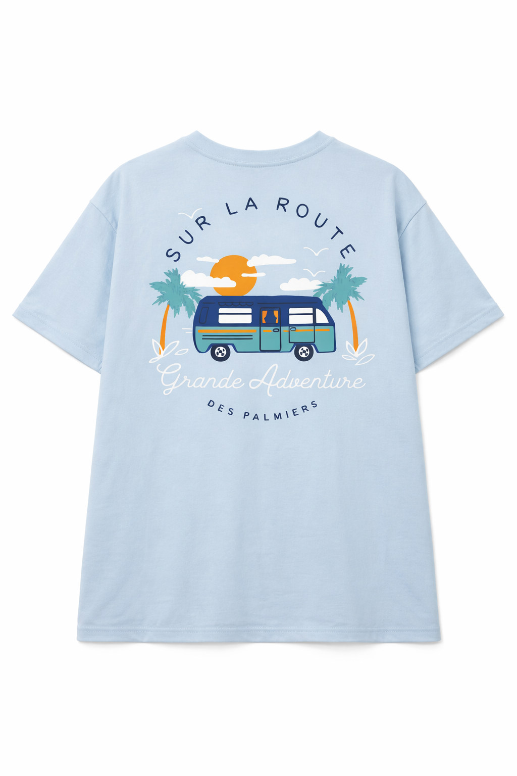 Light blue T-shirt with a graphic of a camper van, two palm trees, a setting sun, clouds, and birds. The text reads 'SUR LA ROUTE', 'Grande Adventure', and 'DES PALMIERS'.