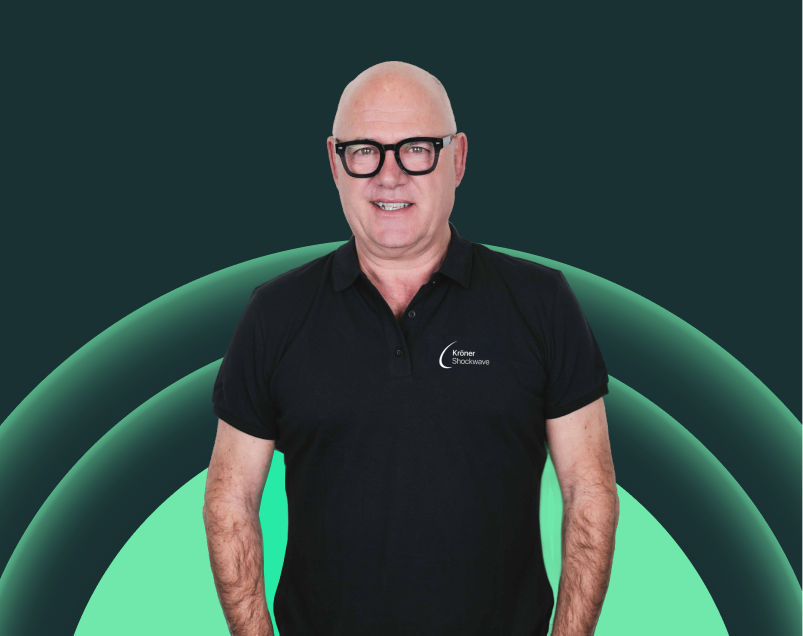 Ein Mann mit Brille trägt ein schwarzes Polo-Shirt vor digitalem grünen Hintergrund