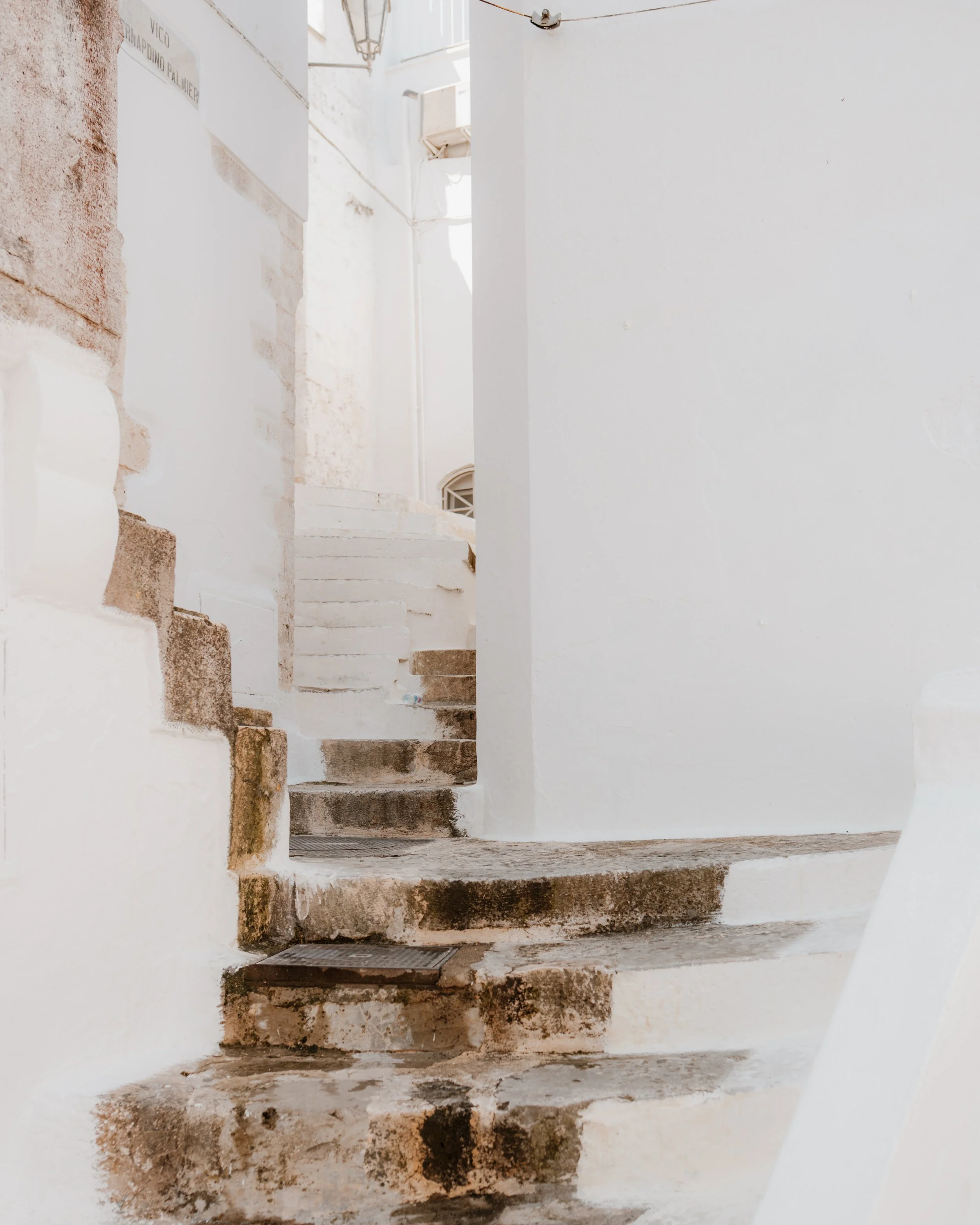 A narrow, whitewashed outdoor staircase with weathered steps in a Mediterranean-style setting.