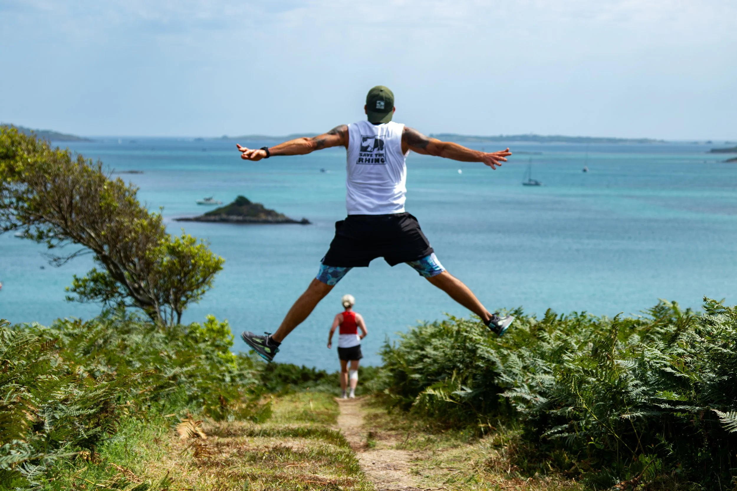 beautiful view of an island with a runner jumping in a start shape with another runner in front now in view