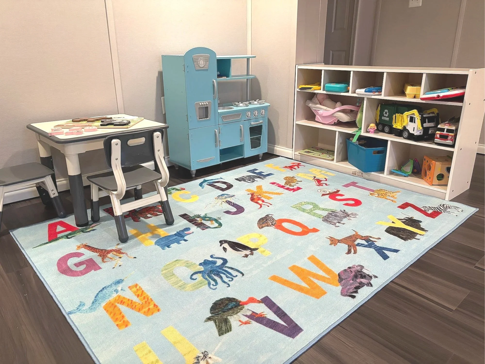 Children's free play area at Watered Pillars. Alphabet rug and pretend play kitchen.