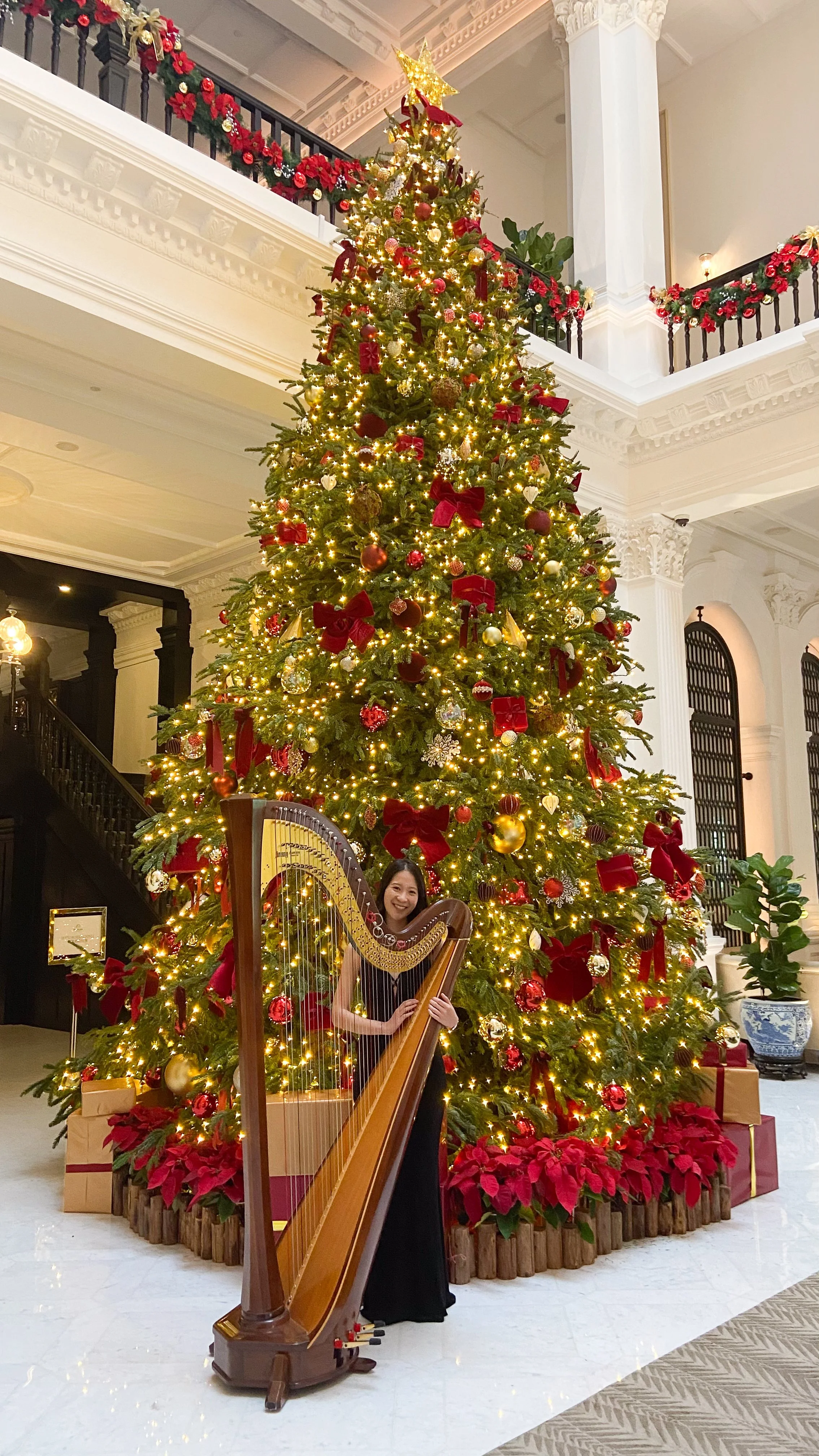 Harpist Katherine Tay standing with her harp at Raffles Hotel, Singapore.