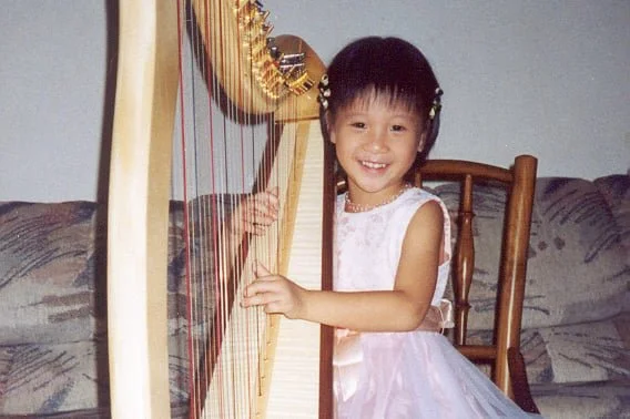 Harpist Katherine Tay, pictured as a child, playing on the harp.