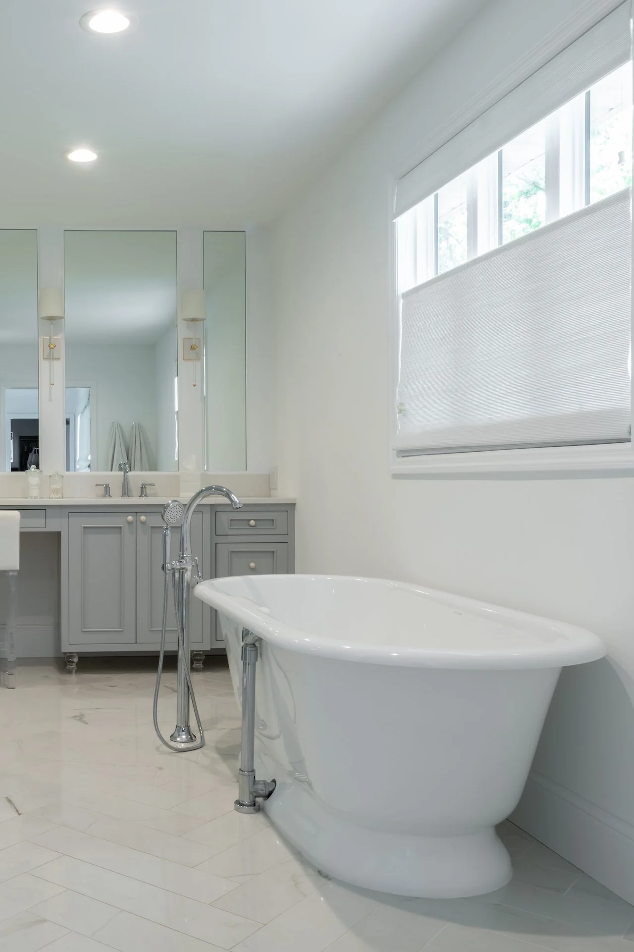 Transitional coastal primary bath with blue-gray cabinets, freestanding tub and walk in shower. 