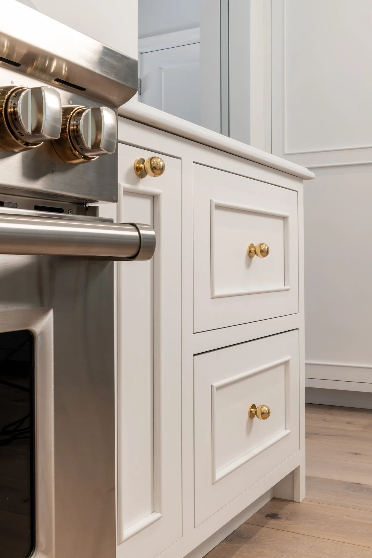 Transitional white inset kitchen with blue bar, professional appliances and brass fixtures. 