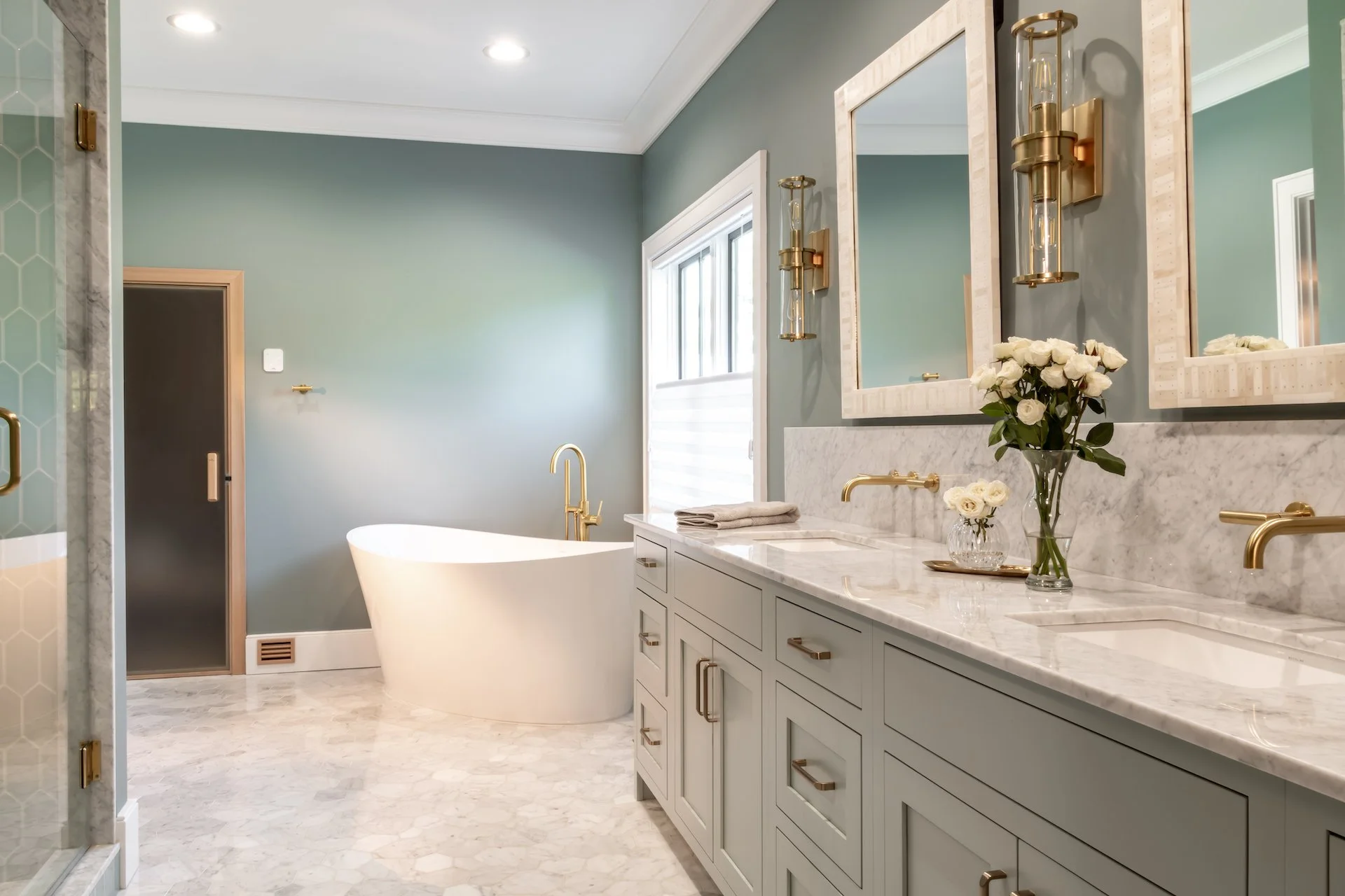 Transitional coastal blue bathroom with marble countertops and gold fixtures. 