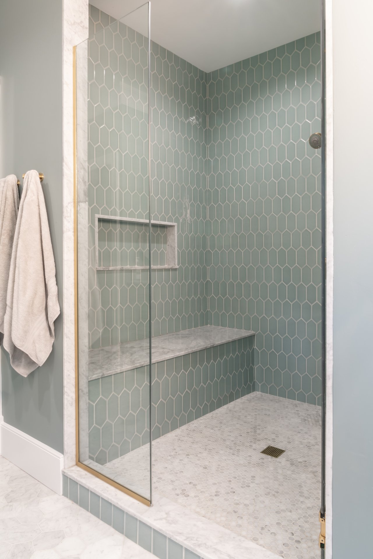 Transitional coastal blue bathroom with marble countertops and gold fixtures. 