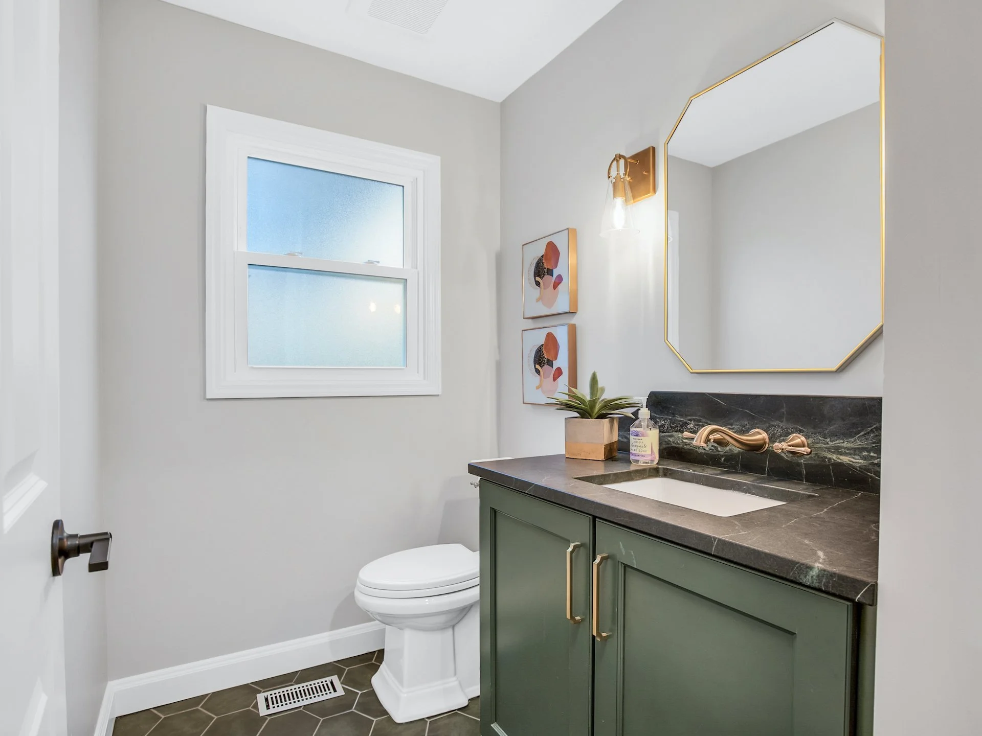 Green vanity with soapstone top and gold fixtures. 