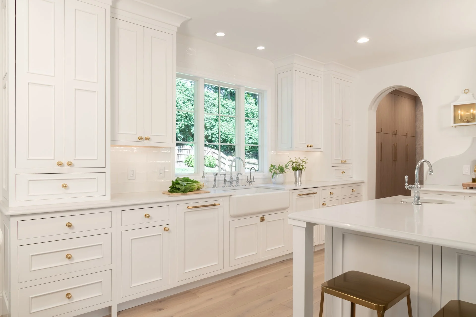 Transitional white inset kitchen with blue bar, professional appliances and brass fixtures. 