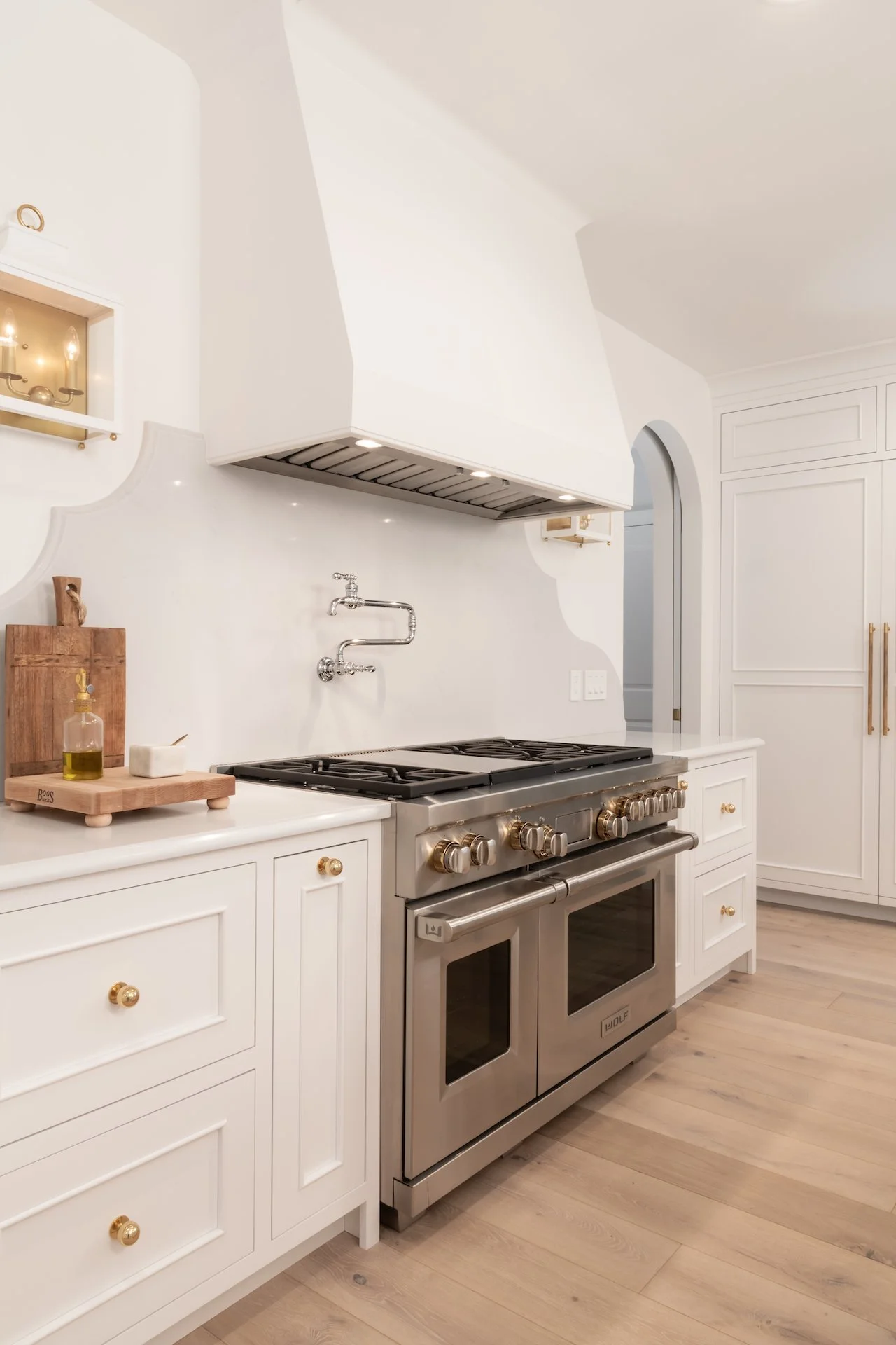 Transitional white inset kitchen with blue bar, professional appliances and brass fixtures. 