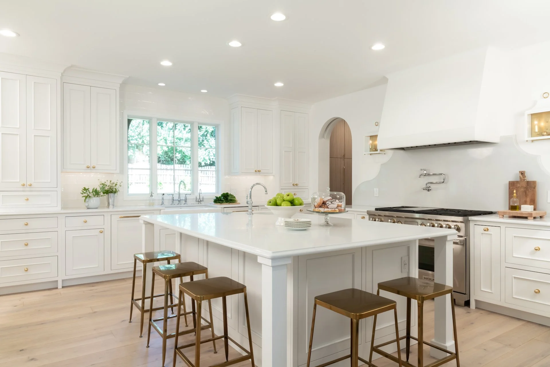 Transitional white inset kitchen with blue bar, professional appliances and brass fixtures. 