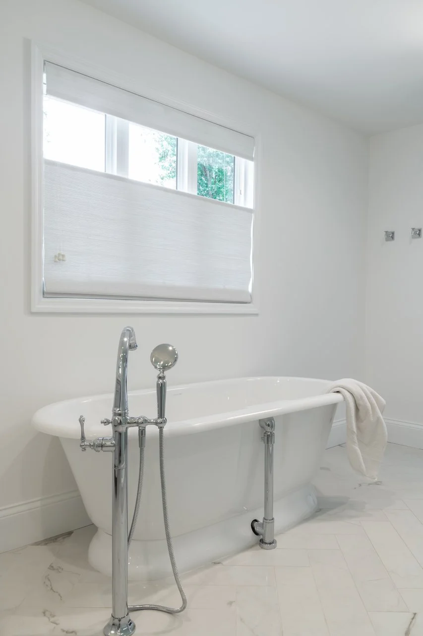 Transitional coastal primary bath with blue-gray cabinets, freestanding tub and walk in shower. 