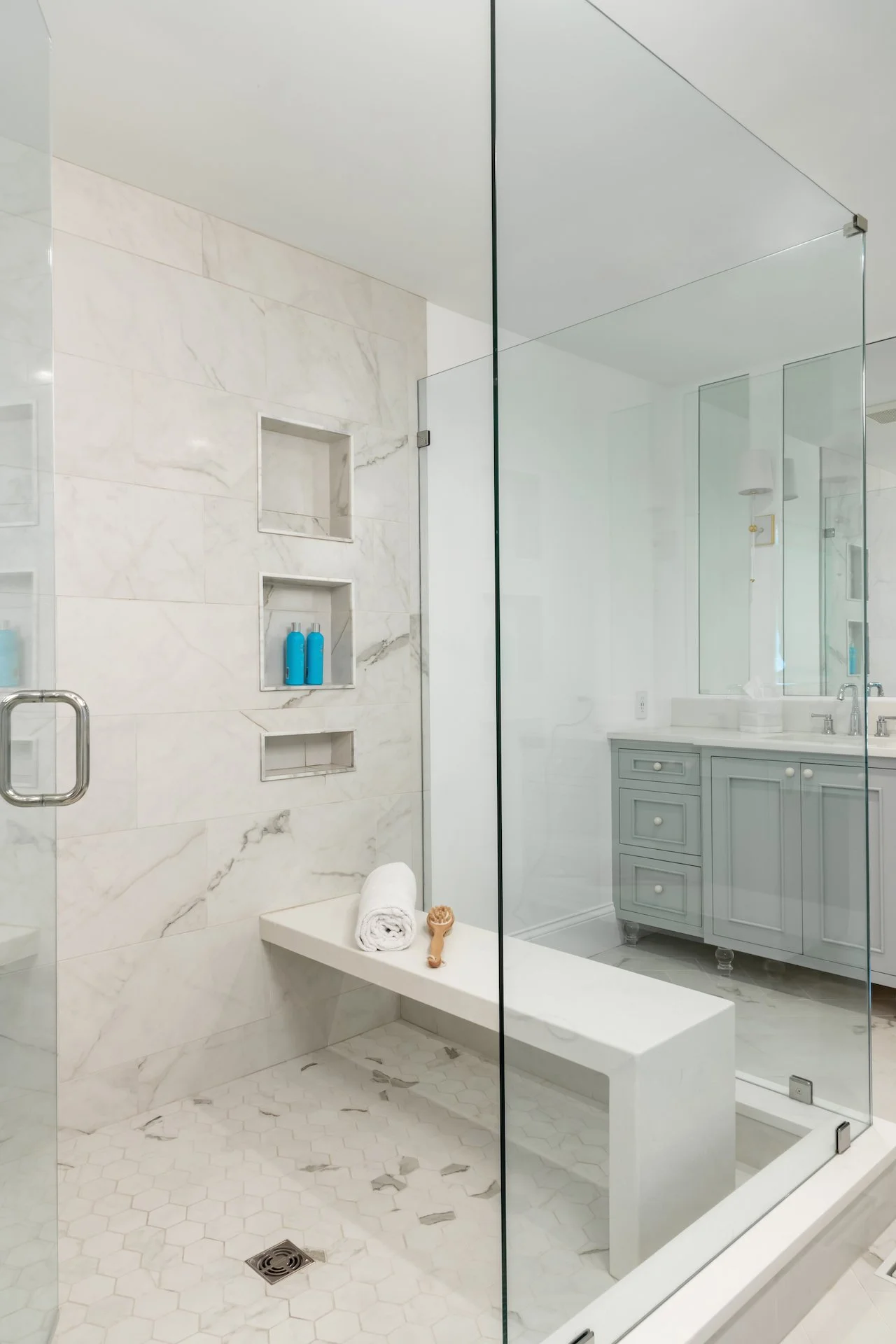 Transitional coastal primary bath with blue-gray cabinets, freestanding tub and walk in shower. 