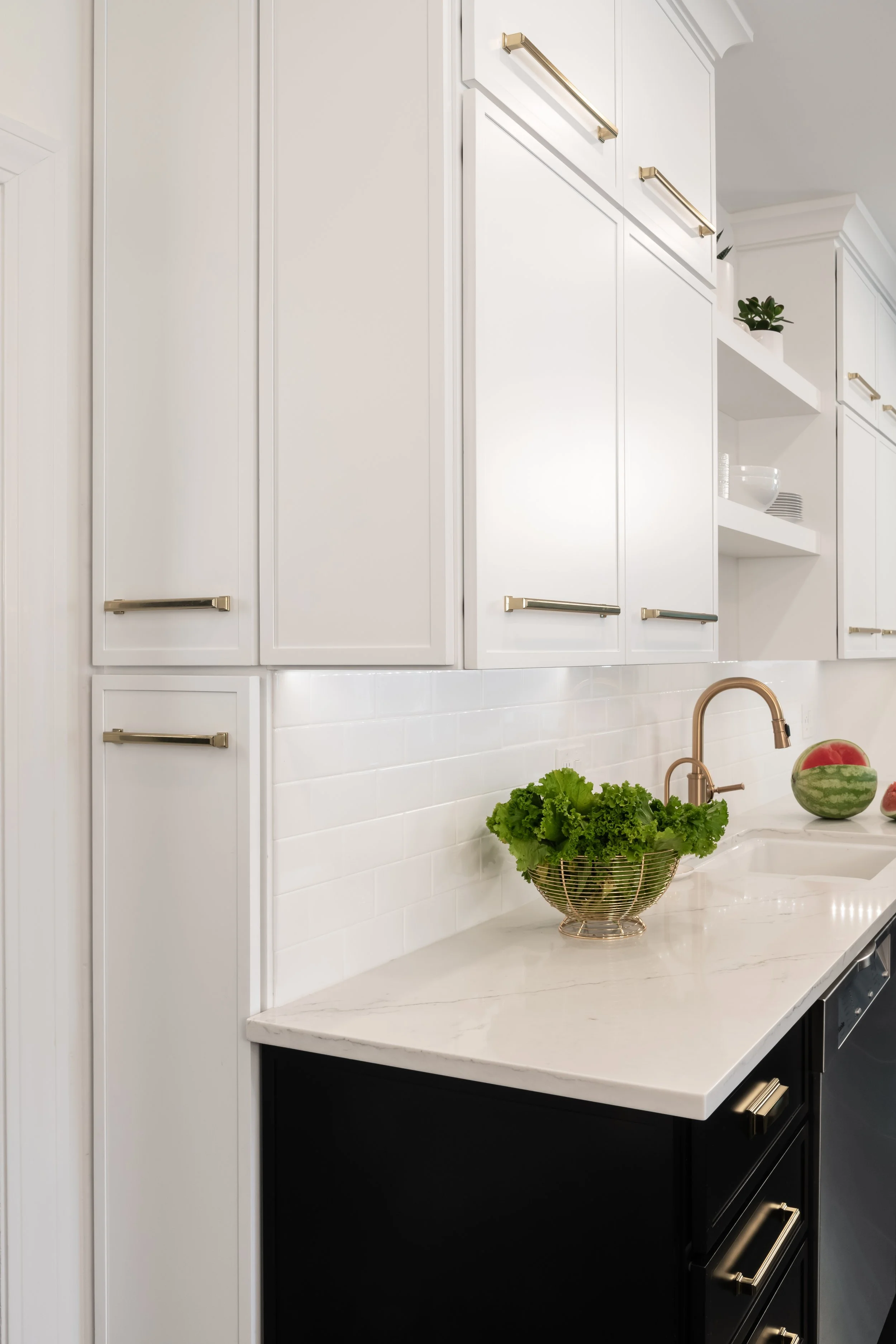 Modern kitchen in a traditional home. Black and white cabinetry and gold fixtures make this kitchen classic while updated and modern. 