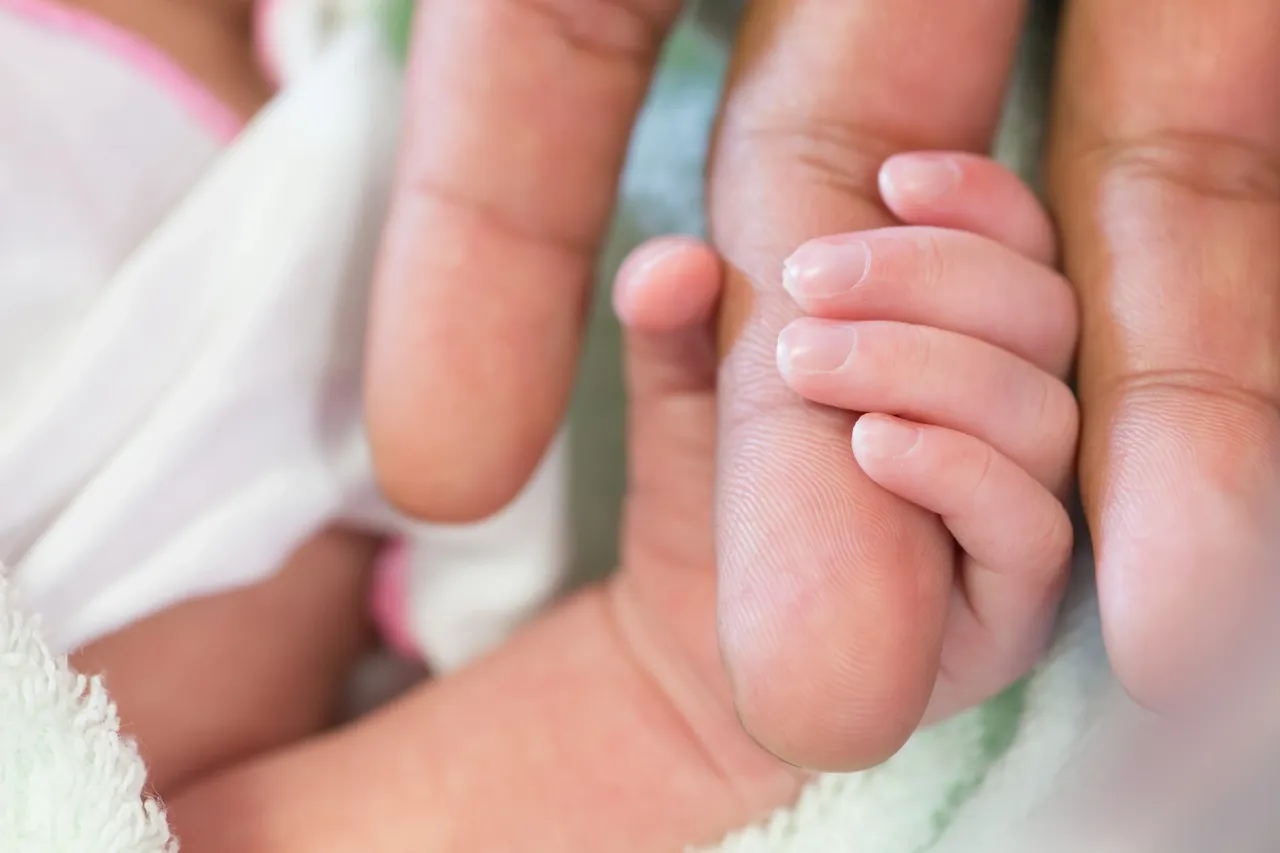 Newborn holding mother's finger.