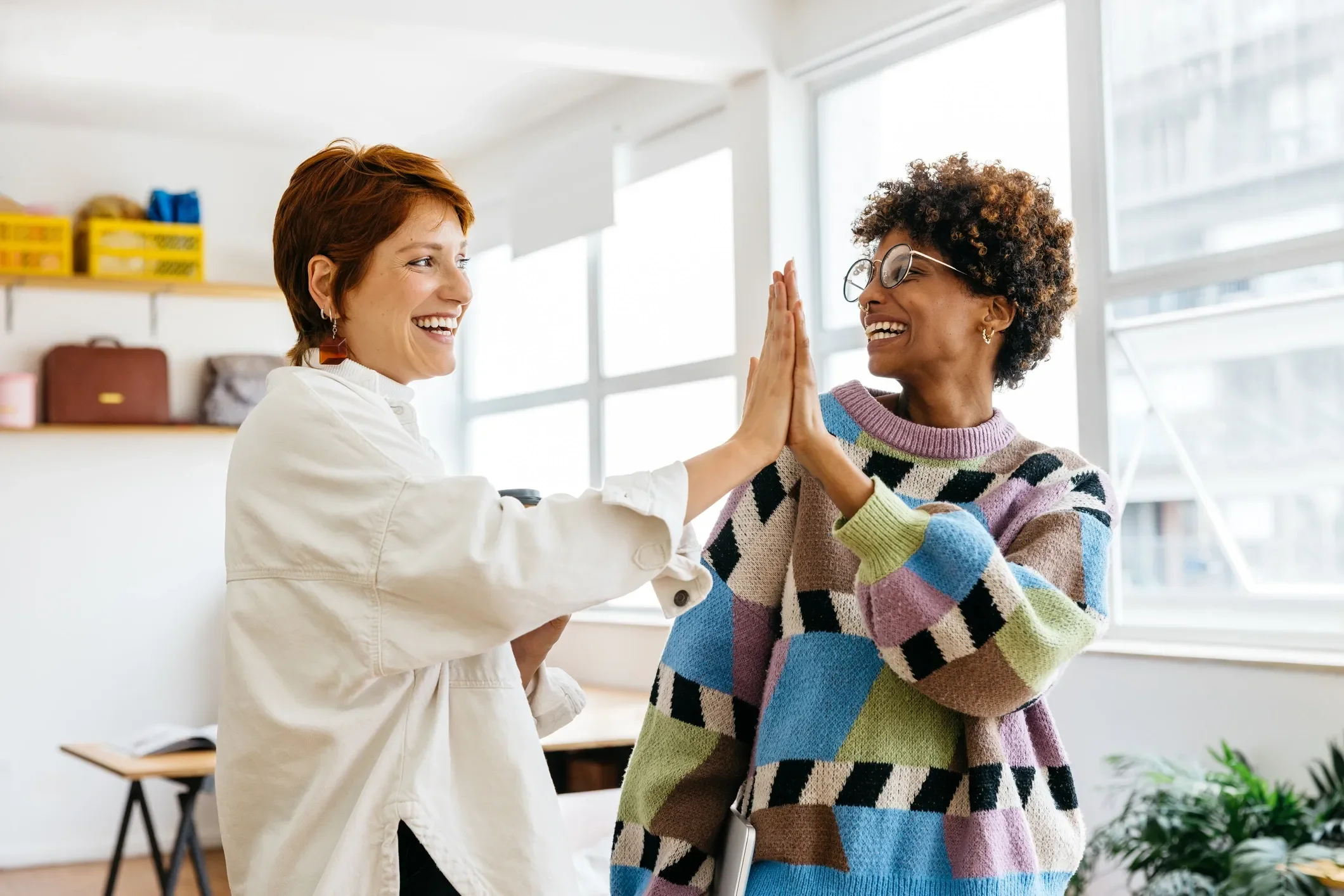 Two moms high five at a motherhood community meetup in Ishpeming, Michigan.