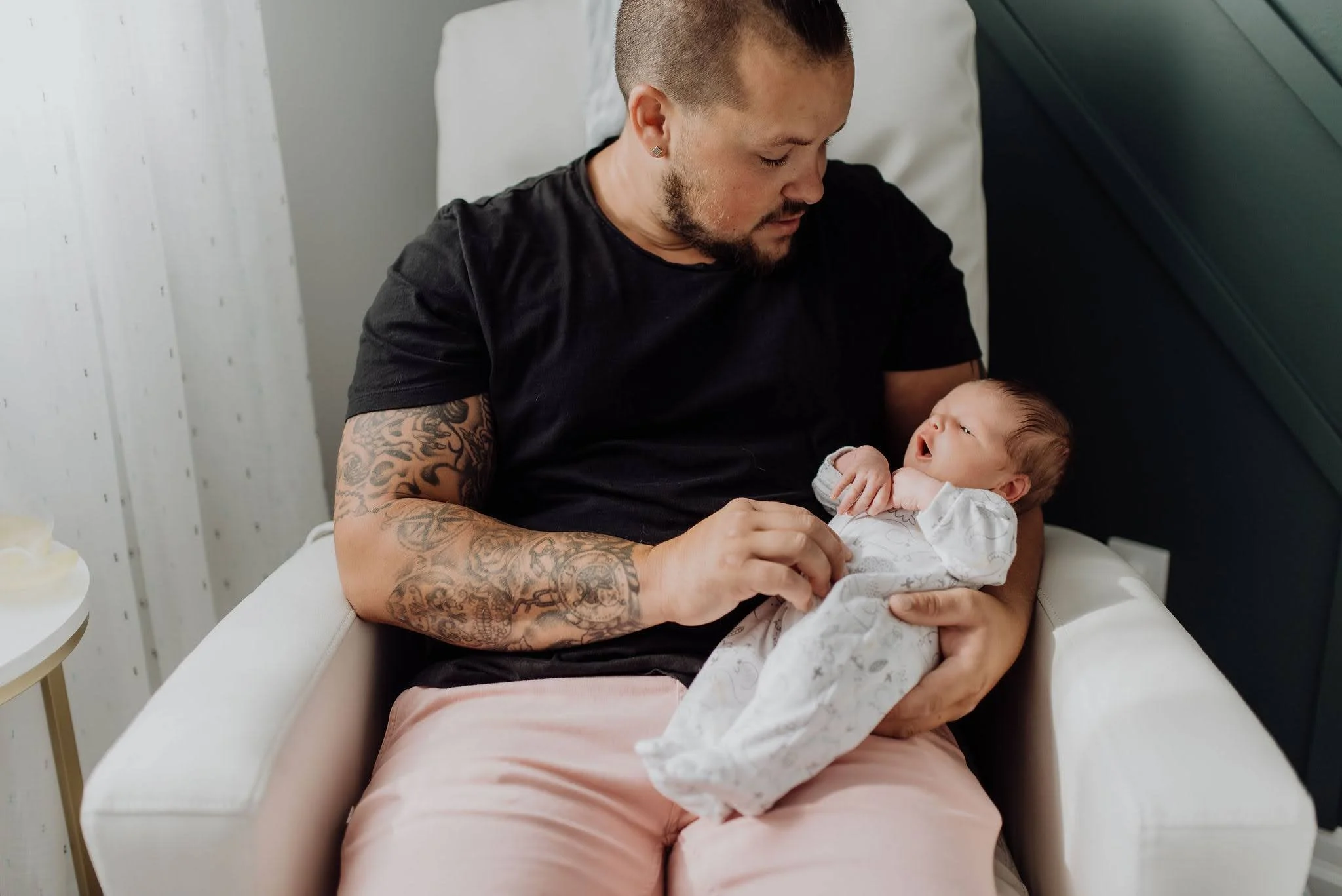 A Houghton county dad holds his newborn baby in a nursery chair.