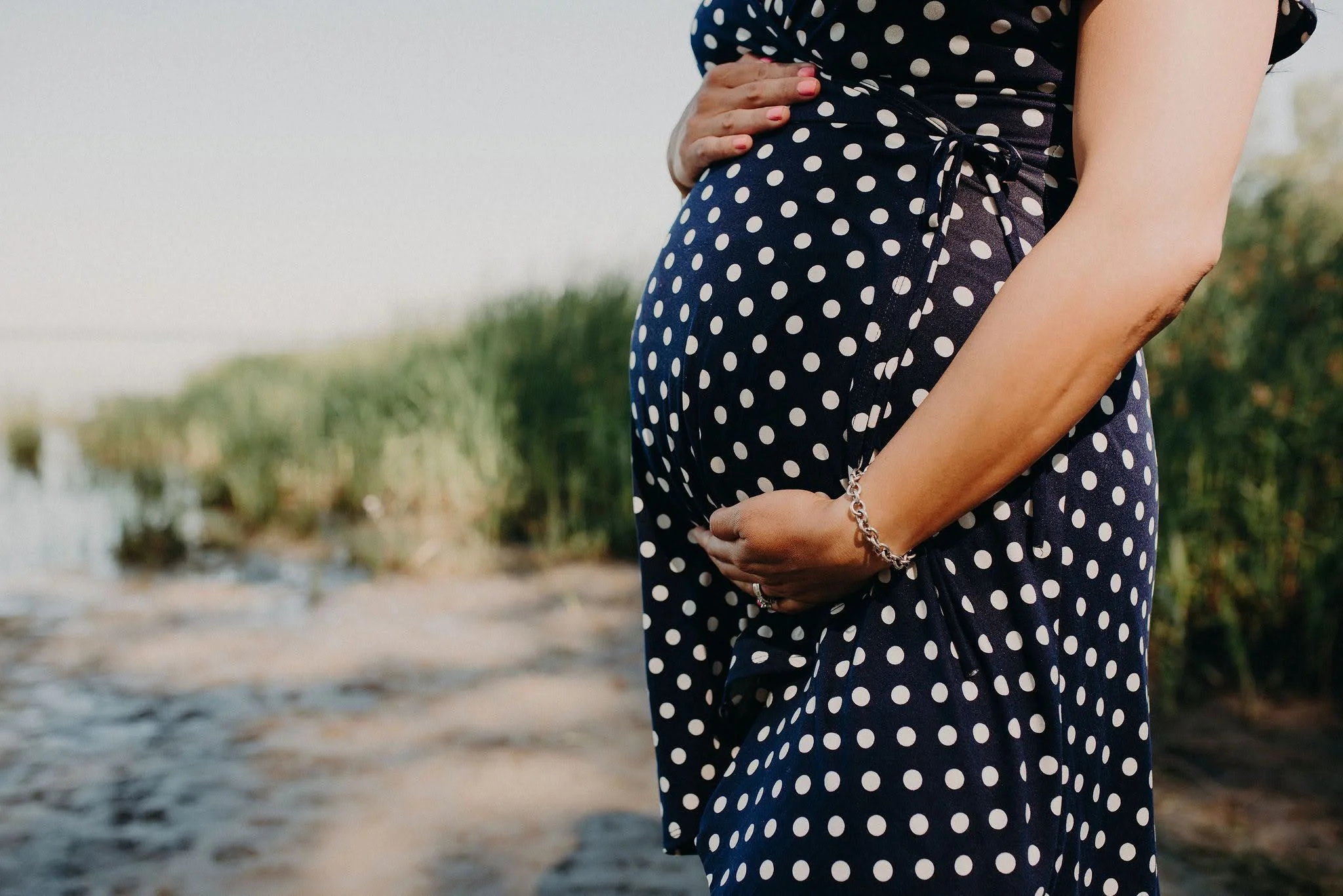 Pregnant woman posing for professional photoshoot in Marquette, Michigan while holding belly.