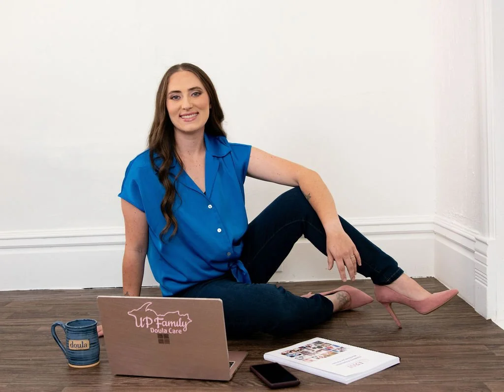 Lacy Anderson of UP Family Doula Care in Marquette posing for professional headshot seated on floor.