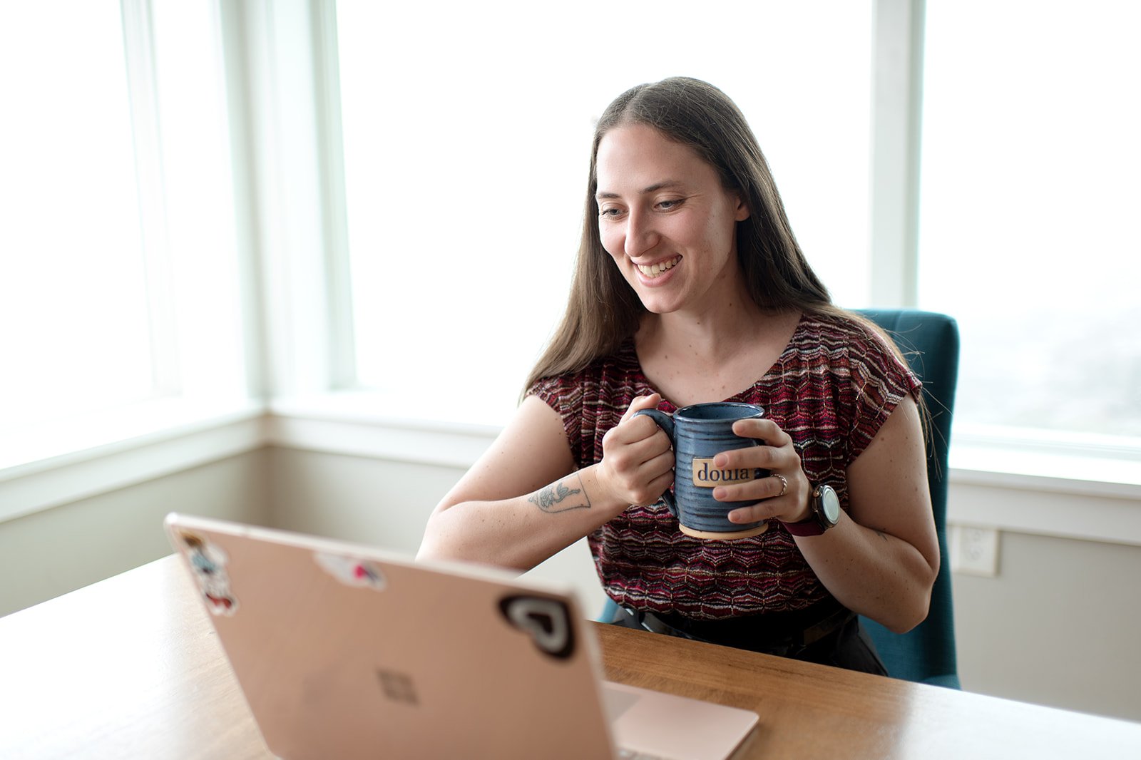 Lacy Anderson, doula mentor, holding coffee during virtual strategy session.