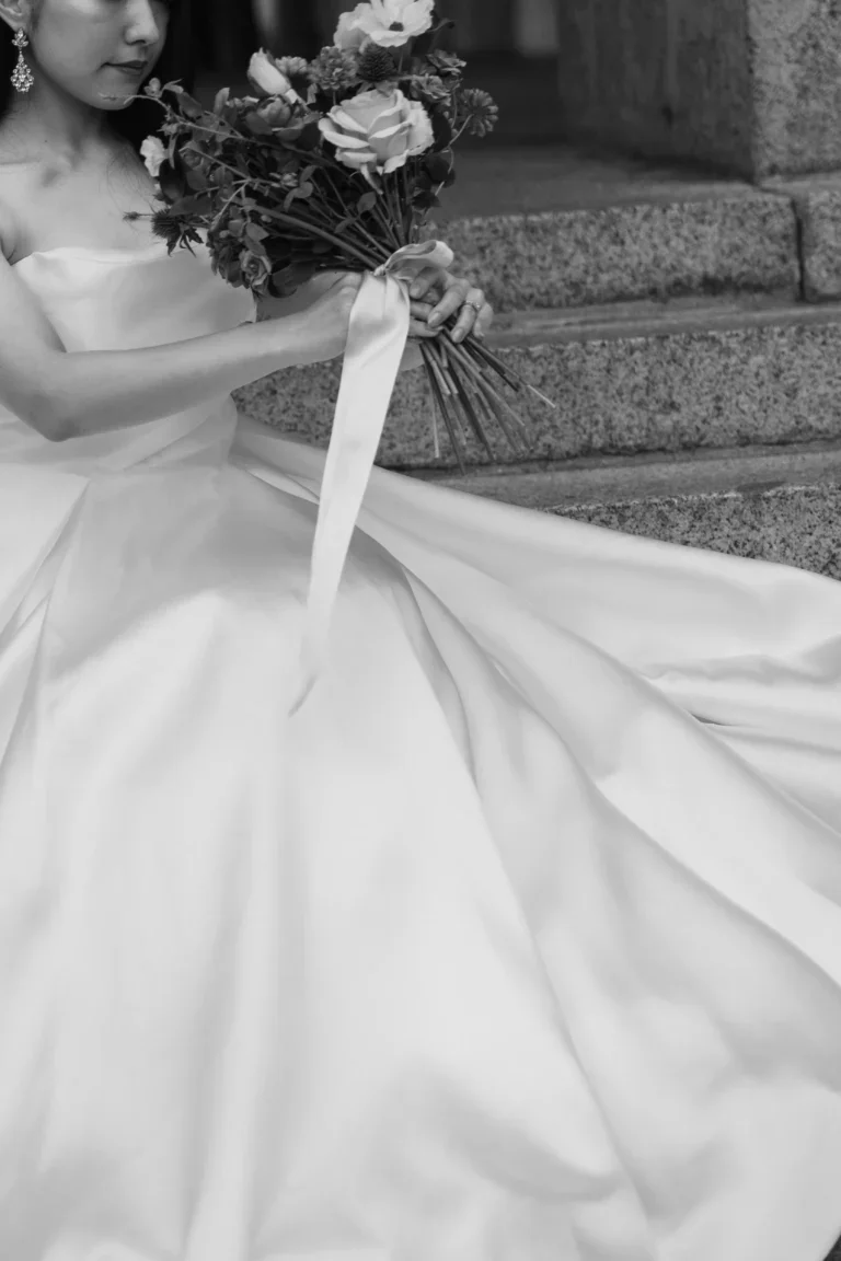 結婚式のドレスを着た女性が花束を持ち、階段に座っている写真