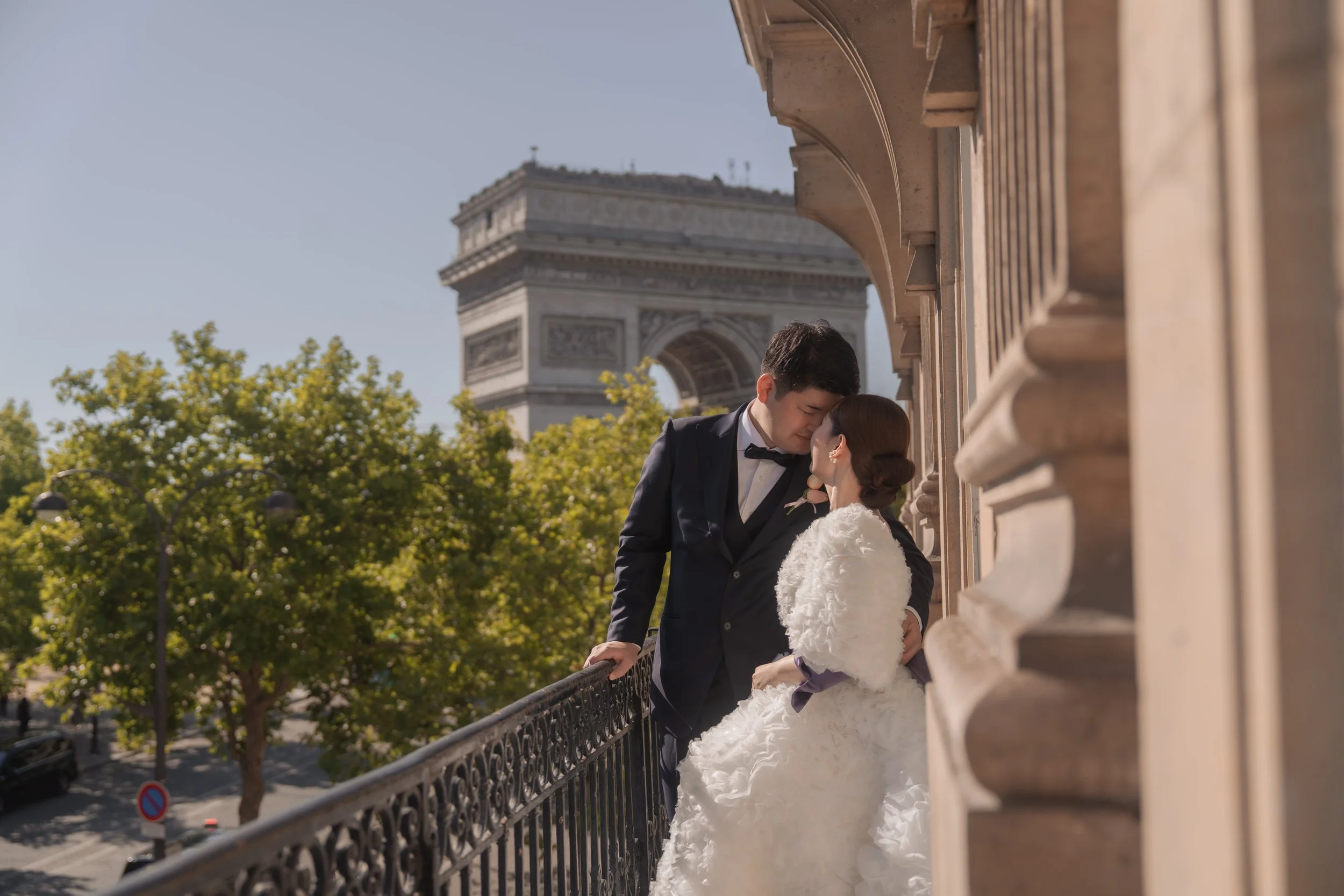 結婚式の夫婦がパリのエッフェル塔の前のバルコニーで抱き合っている情景