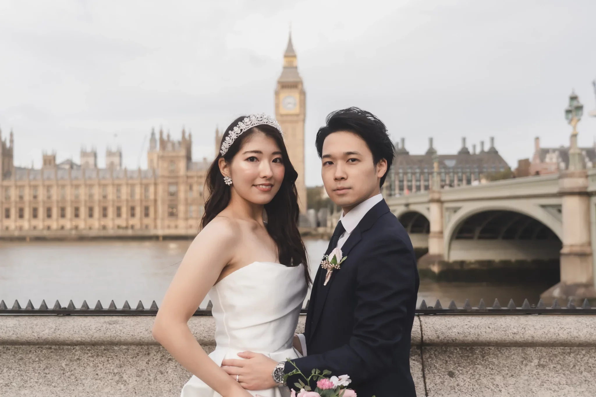 結婚式のカップルがロンドンのビッグベン寺院前で写真を撮っている。