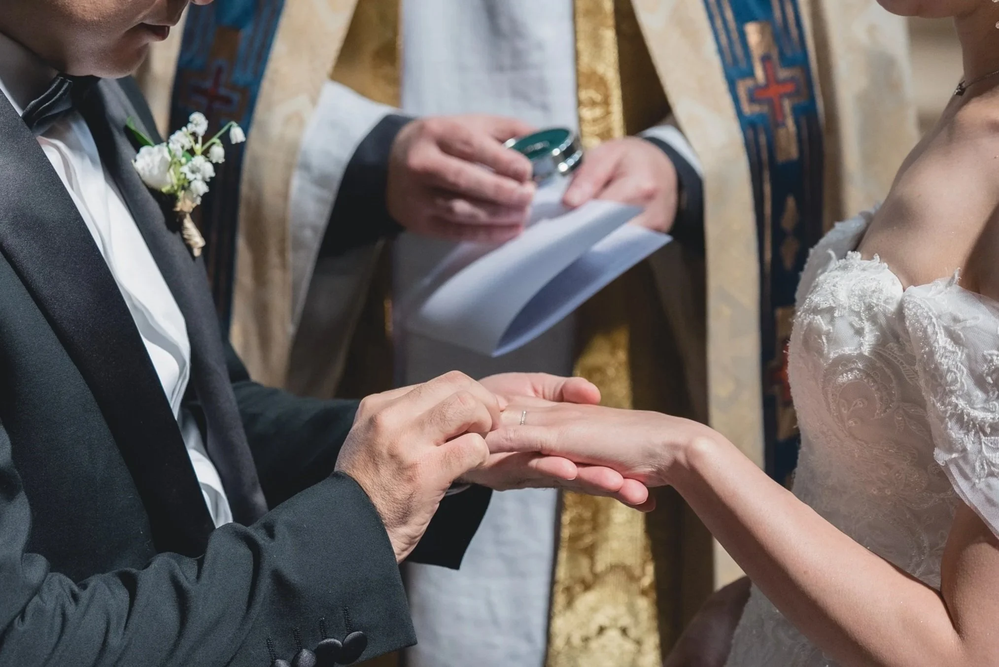 結婚式の場面で、新郎が新婦の手に指輪をはめているシーン