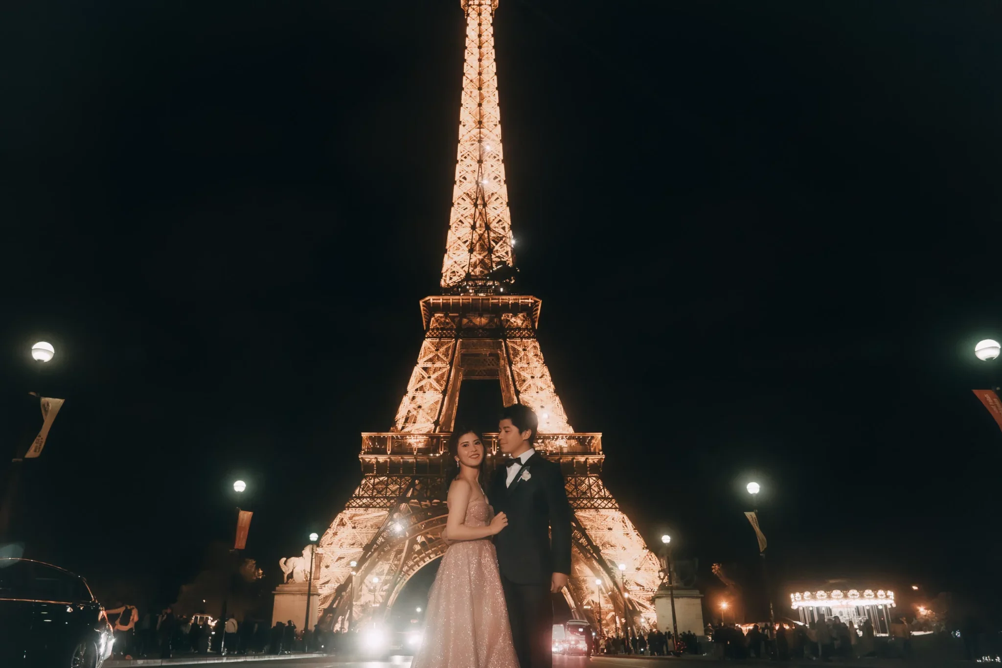夜のエッフェル塔の前でカップルが写真を撮っている