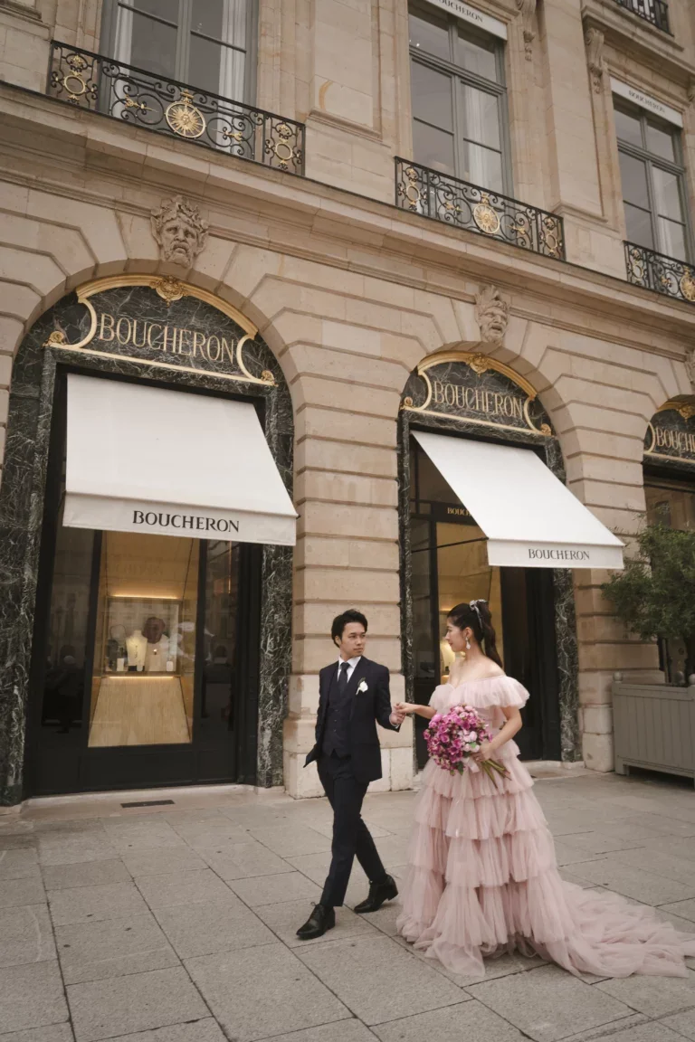 結婚式のカップルがパリのブシュロン店舗の前で手をつないで歩いている写真