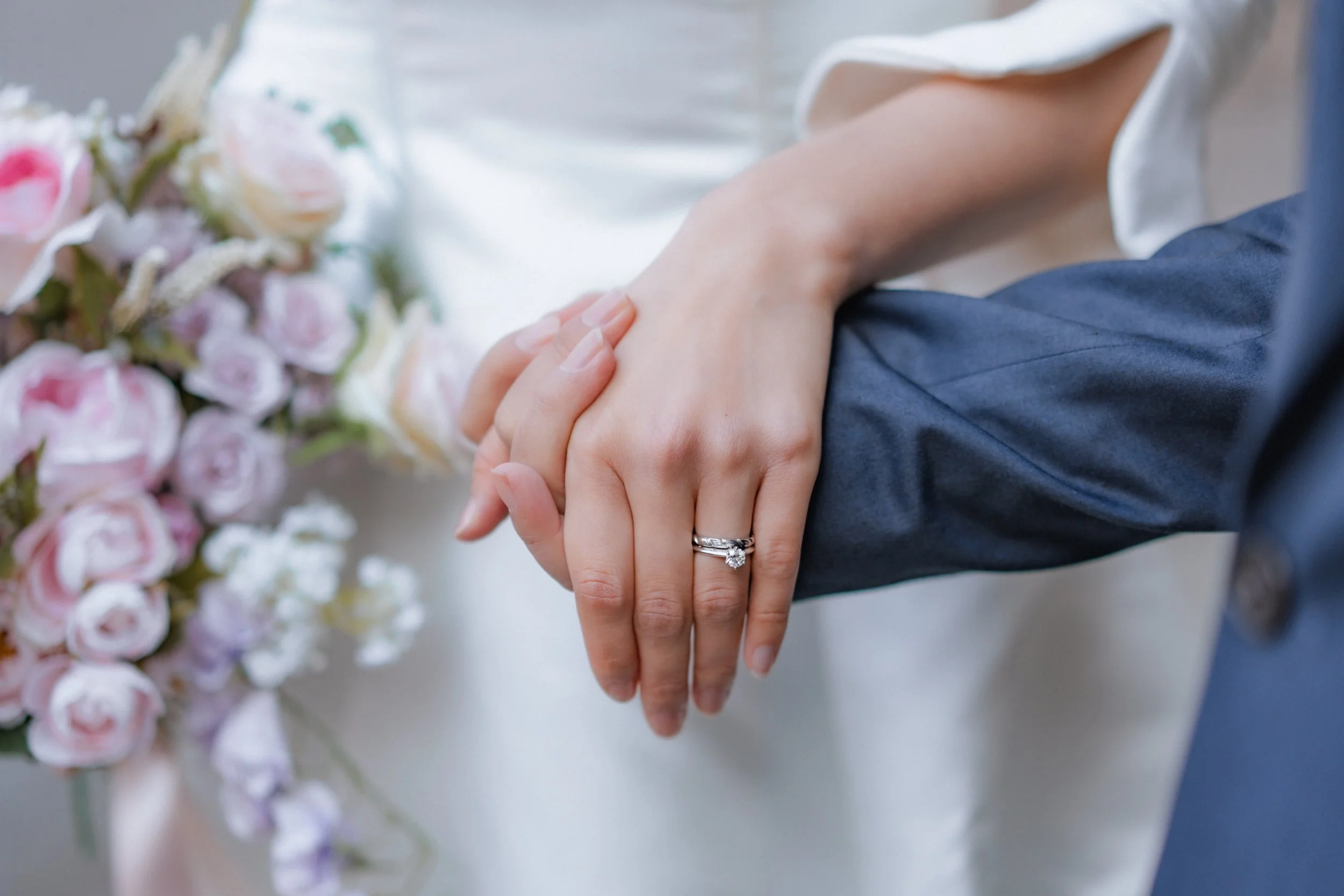 結婚式の指輪交換をしている新郎新婦の手とブーケ