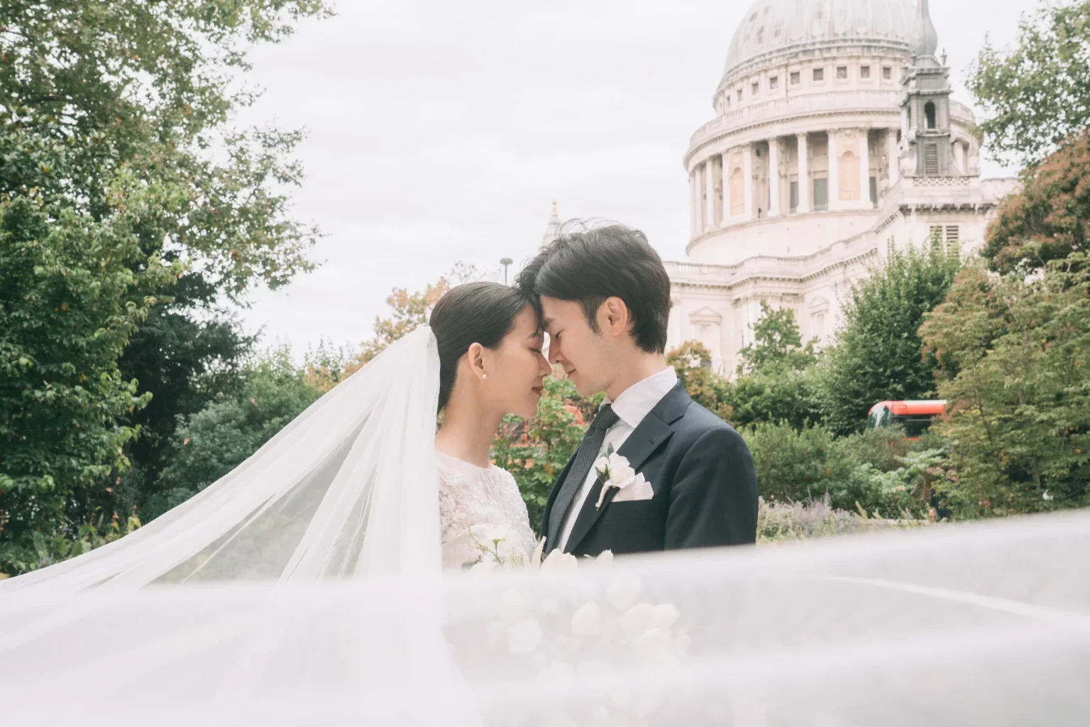 結婚式を挙げている夫婦が顔を近づけているシーン。背景にイギリスのロンドンにあるセント・ポール大聖堂が見える。
