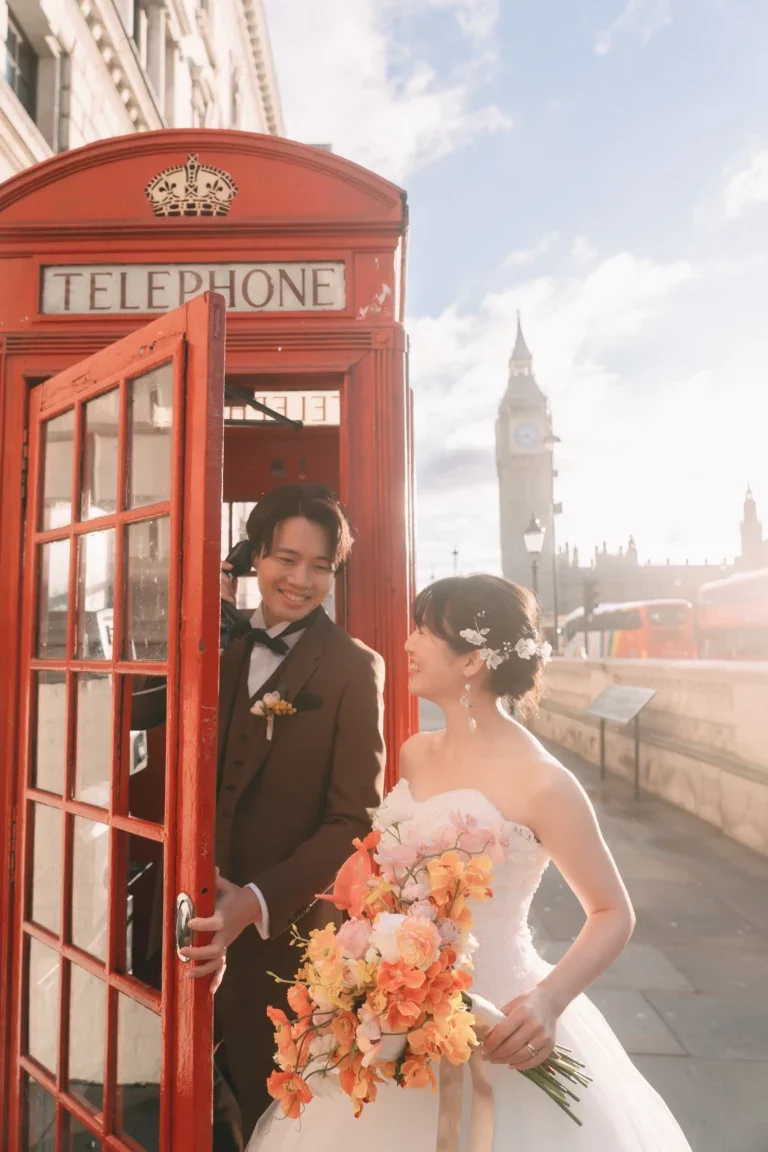 ロンドンのビッグベンと赤い電話ボックスの前で、新郎新婦が笑顔で話している