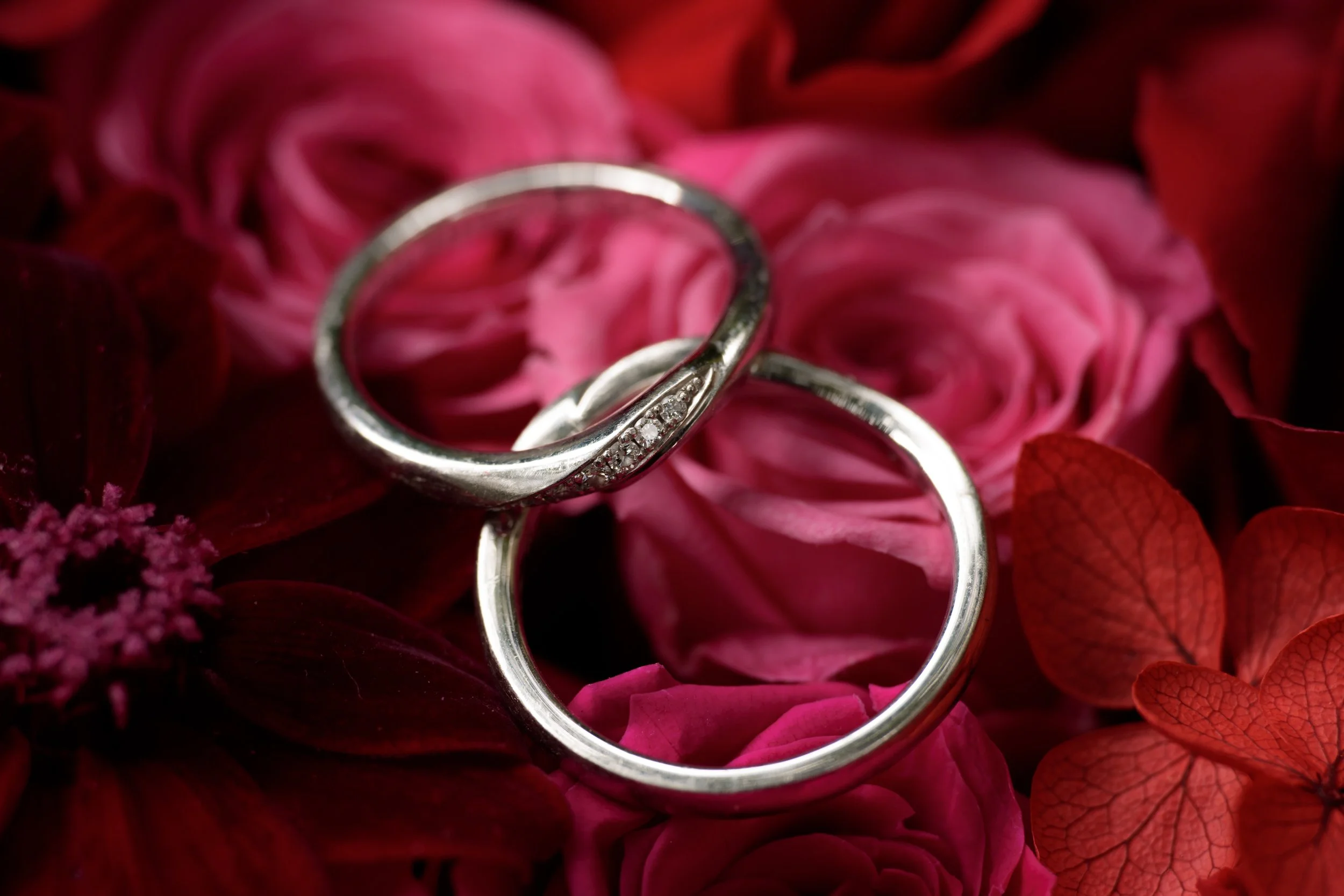 ピンクと紫の花の中に重ねられた二つの結婚指輪